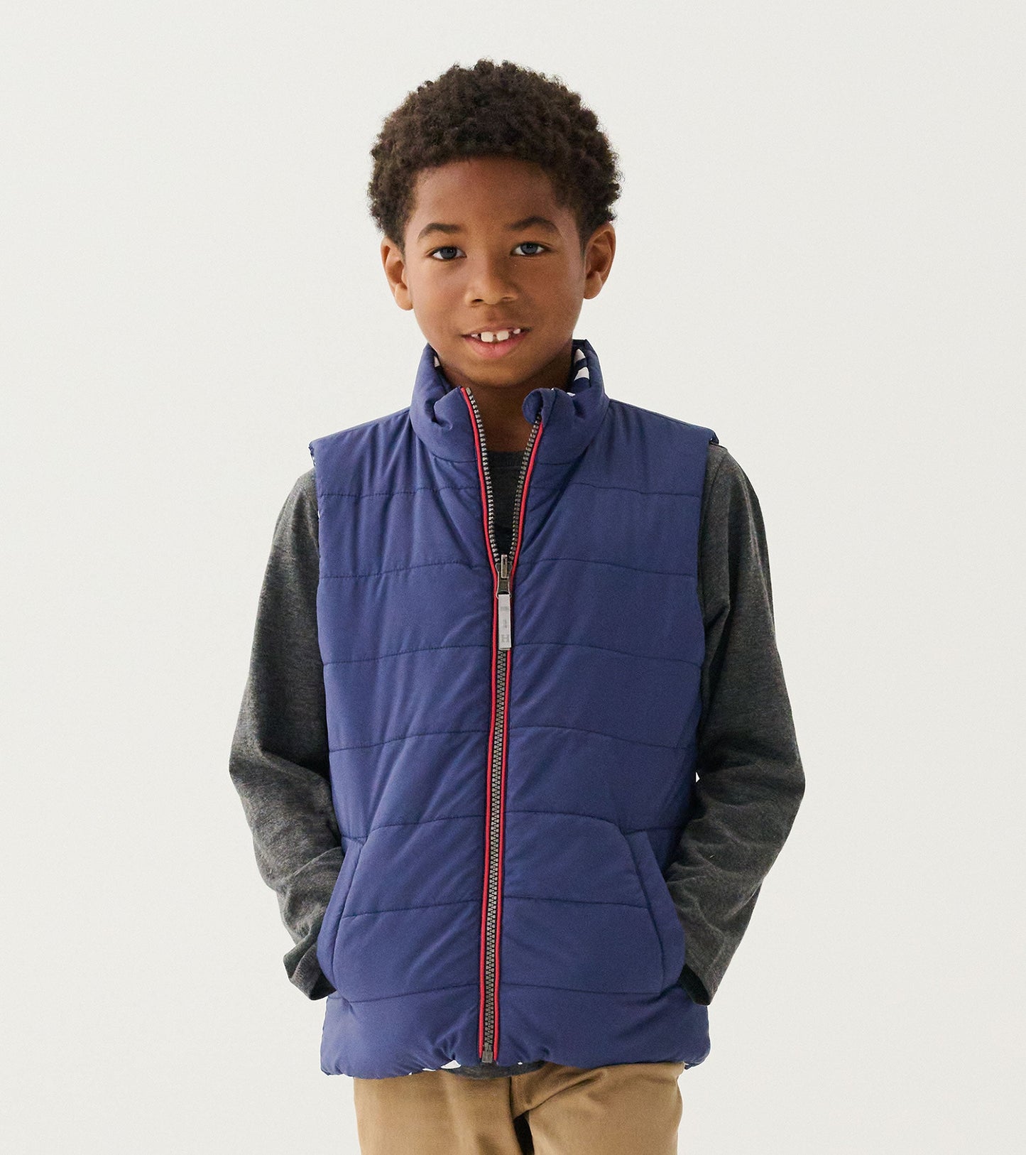 Reversible quilted vest in navy with a zip front, featuring a classic design and side pockets, worn over a gray shirt.