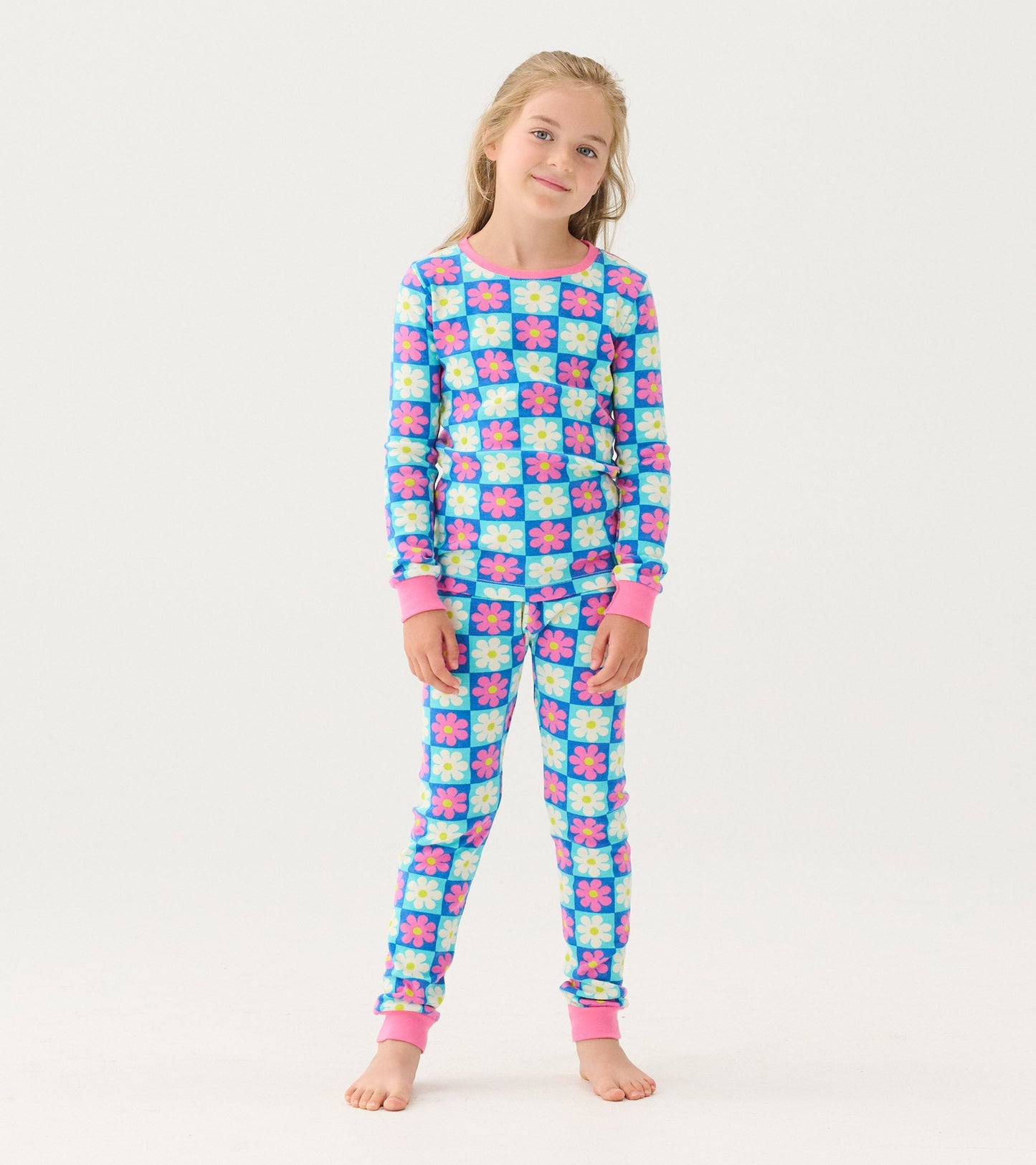 Girls' organic cotton pajama set featuring a colorful checkered pattern with daisies and pink cuffs.