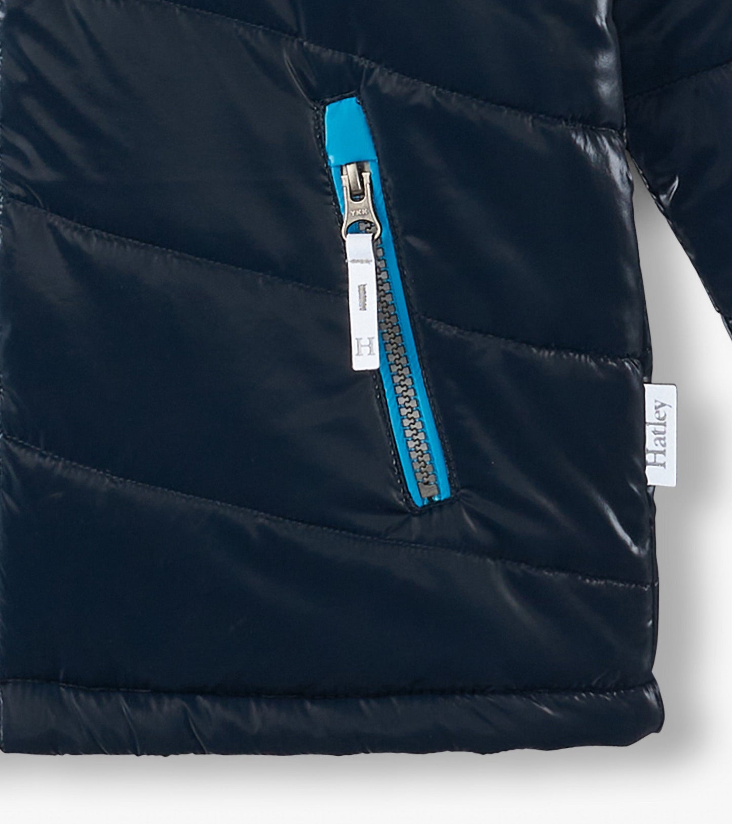 Navy puffer jacket with a chevron pattern and a bright blue zipper pocket, designed for boys.
