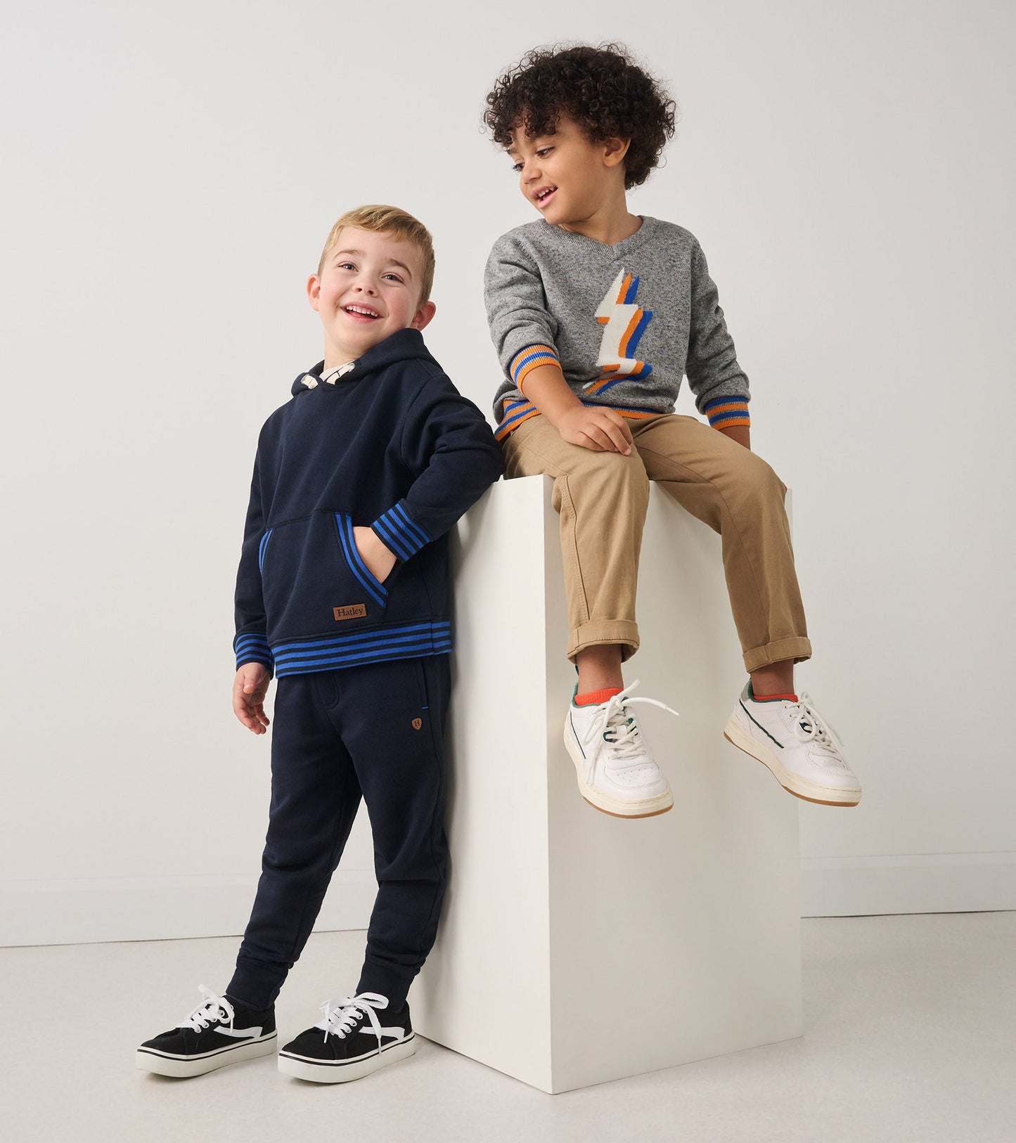 Navy pullover with blue stripes, paired with matching pants; gray sweater with lightning bolt design, worn with khaki pants.