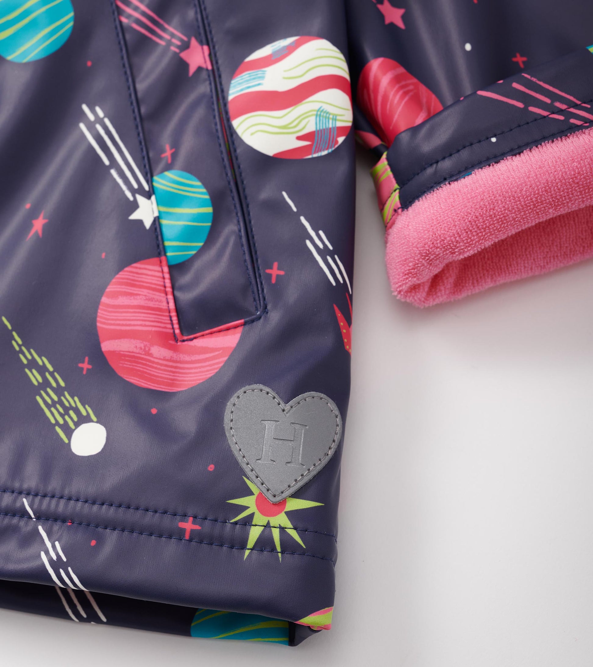 Navy zip-up rain jacket featuring colorful space-themed prints and a pink fleece lining at the cuffs.