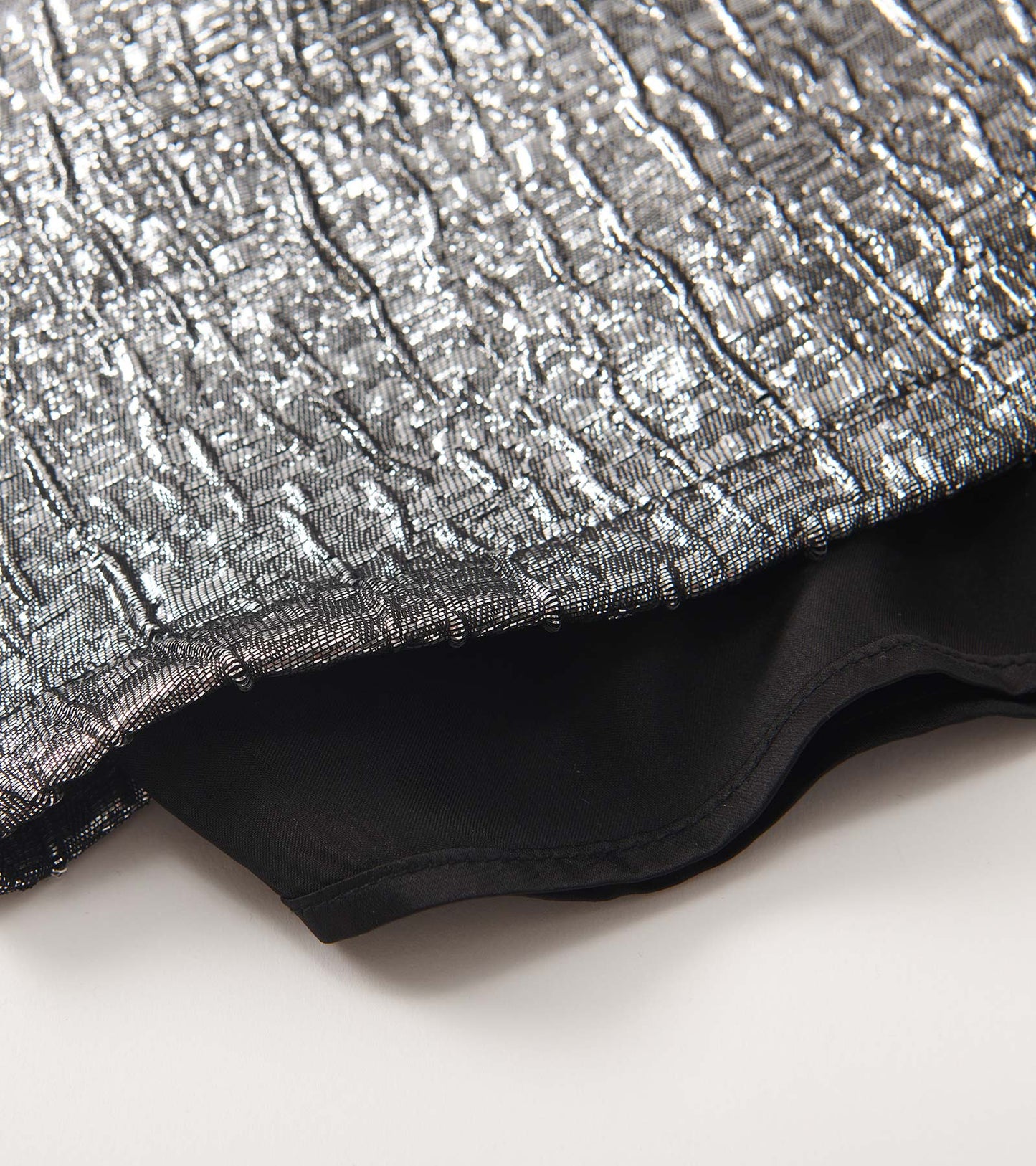 Silver faux fur jacquard dress with a textured pattern and black lining, showcasing the fabric's sheen and detail.