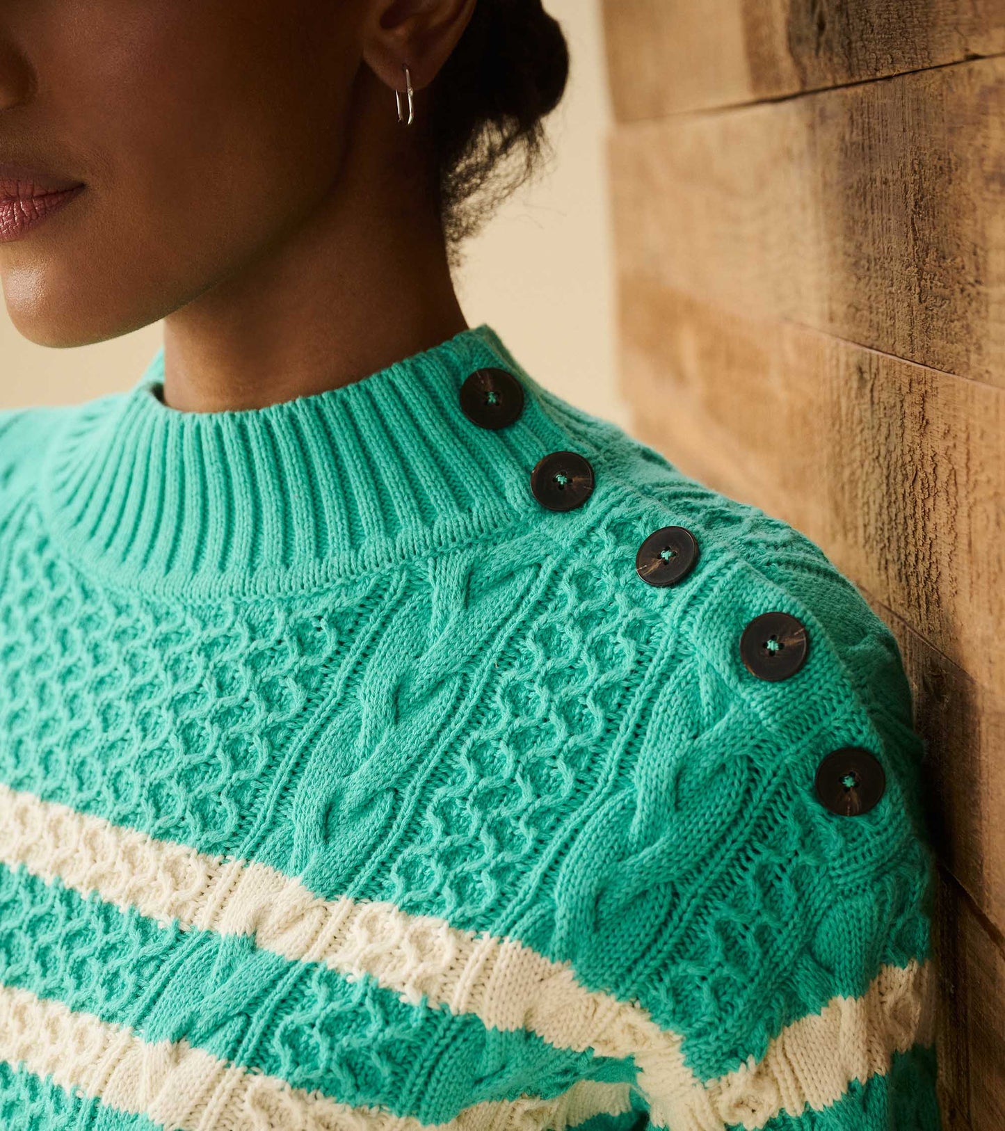 Turquoise sweater with cable knit pattern and white stripes, featuring button details on the shoulder.