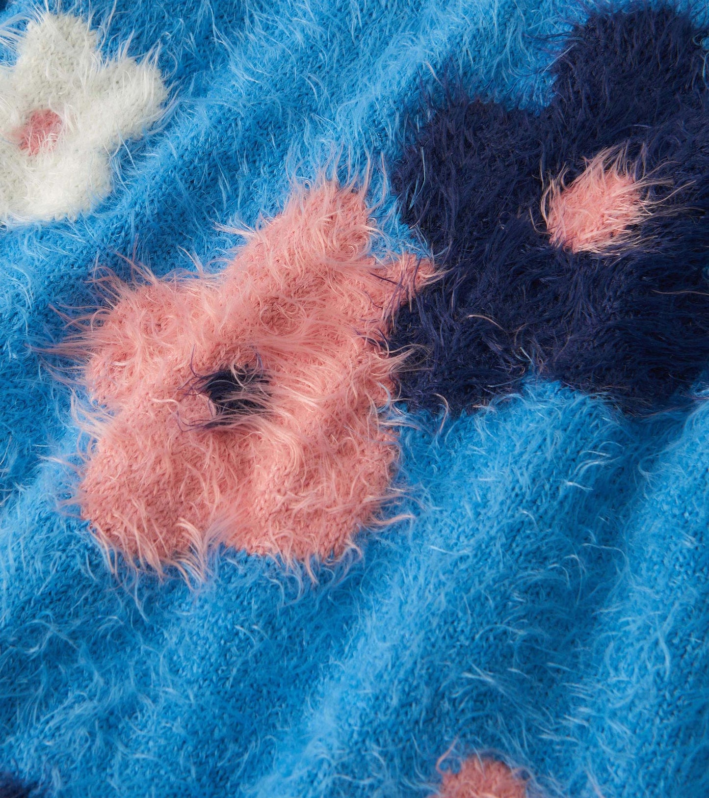 Furry sweater in blue with pink and white floral clusters, featuring a soft texture and playful design.