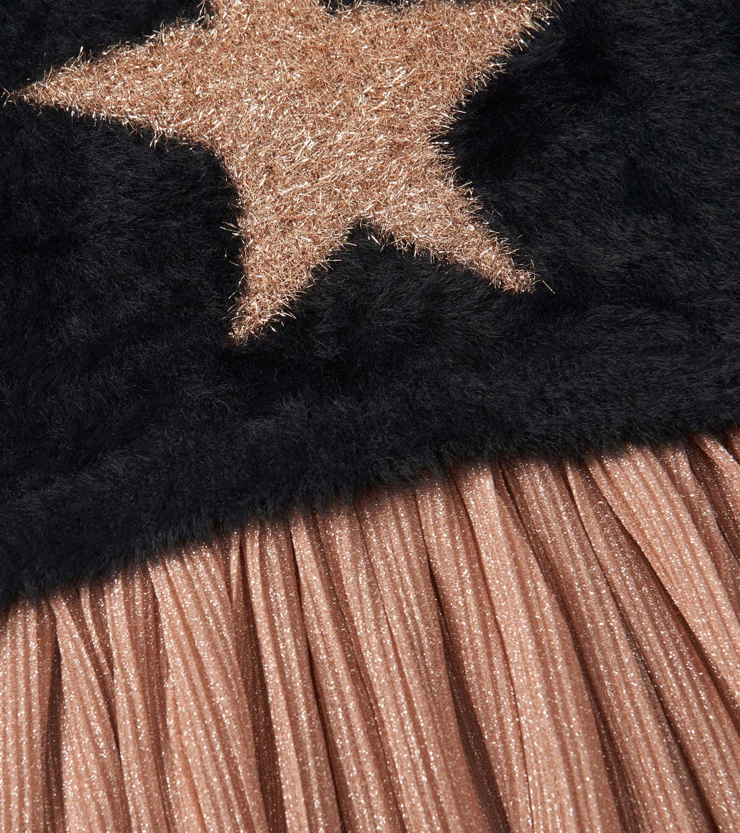 Black dress featuring a plush top with a gold star and a pleated, shimmery rose gold skirt.