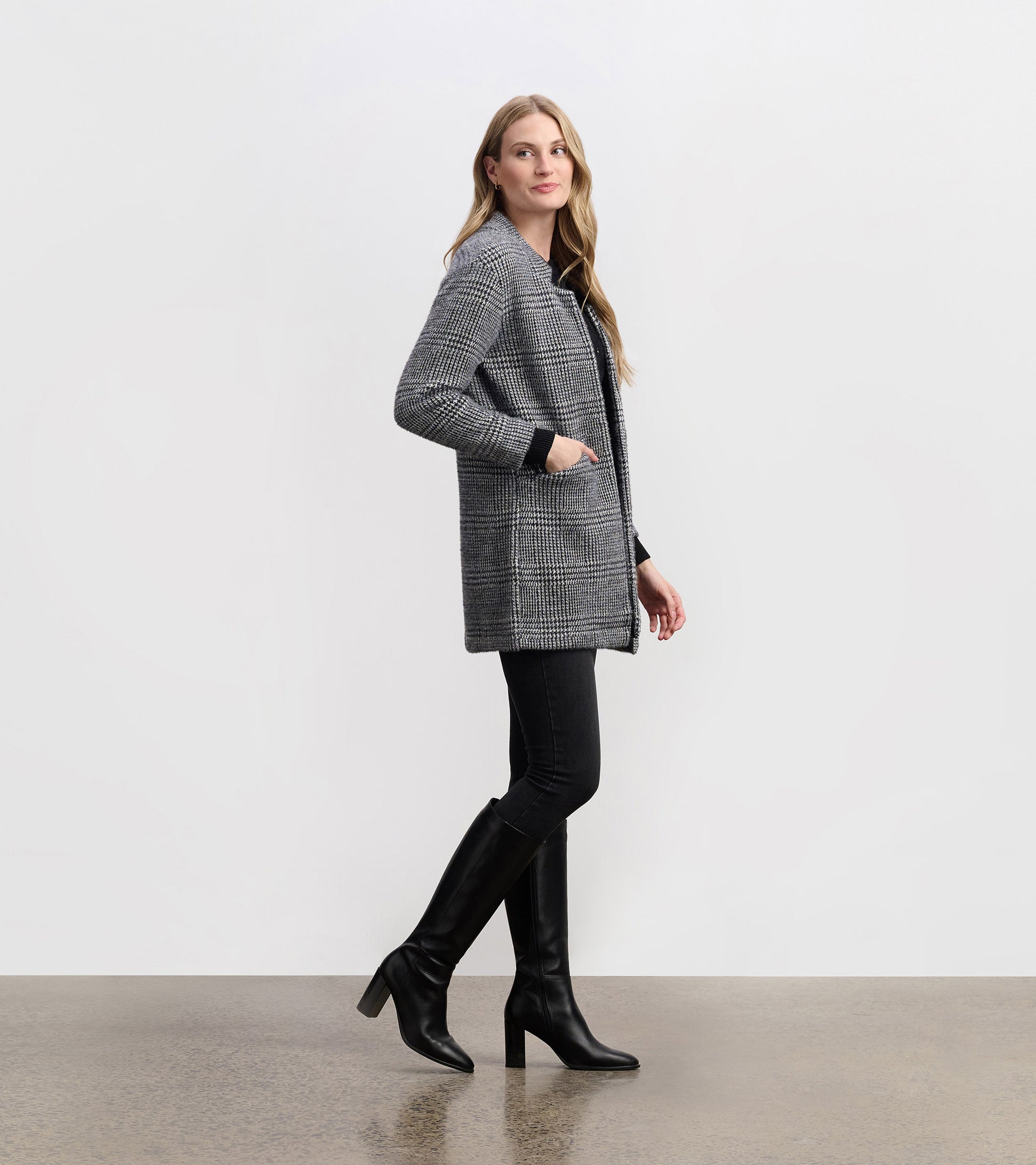 Cozy black check open blazer with a relaxed fit, featuring side pockets and a collar, styled with black jeans and boots.