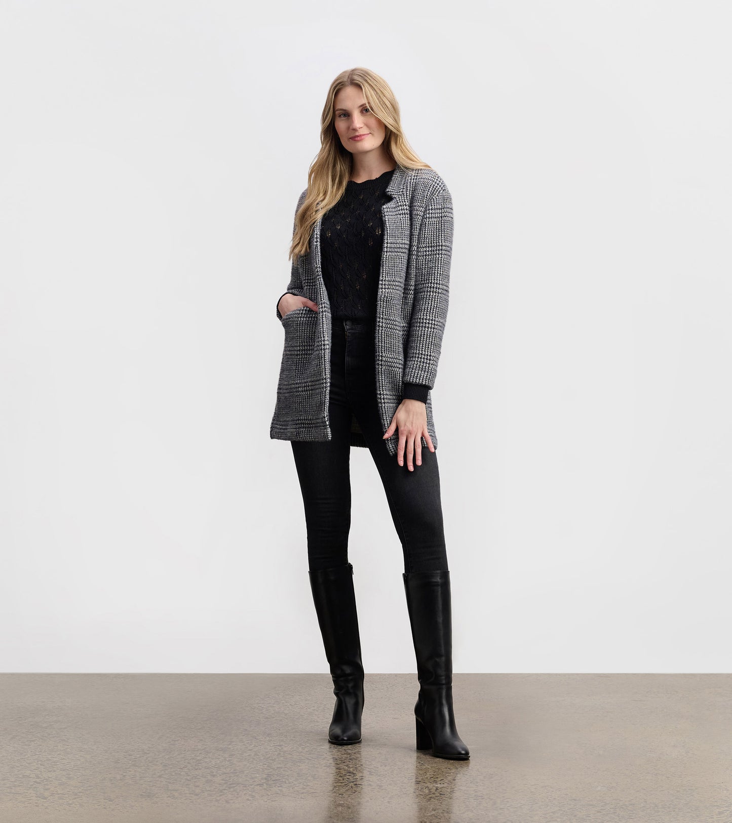 Black check open blazer with a relaxed fit, featuring pockets and a stylish collar, paired with black jeans and boots.