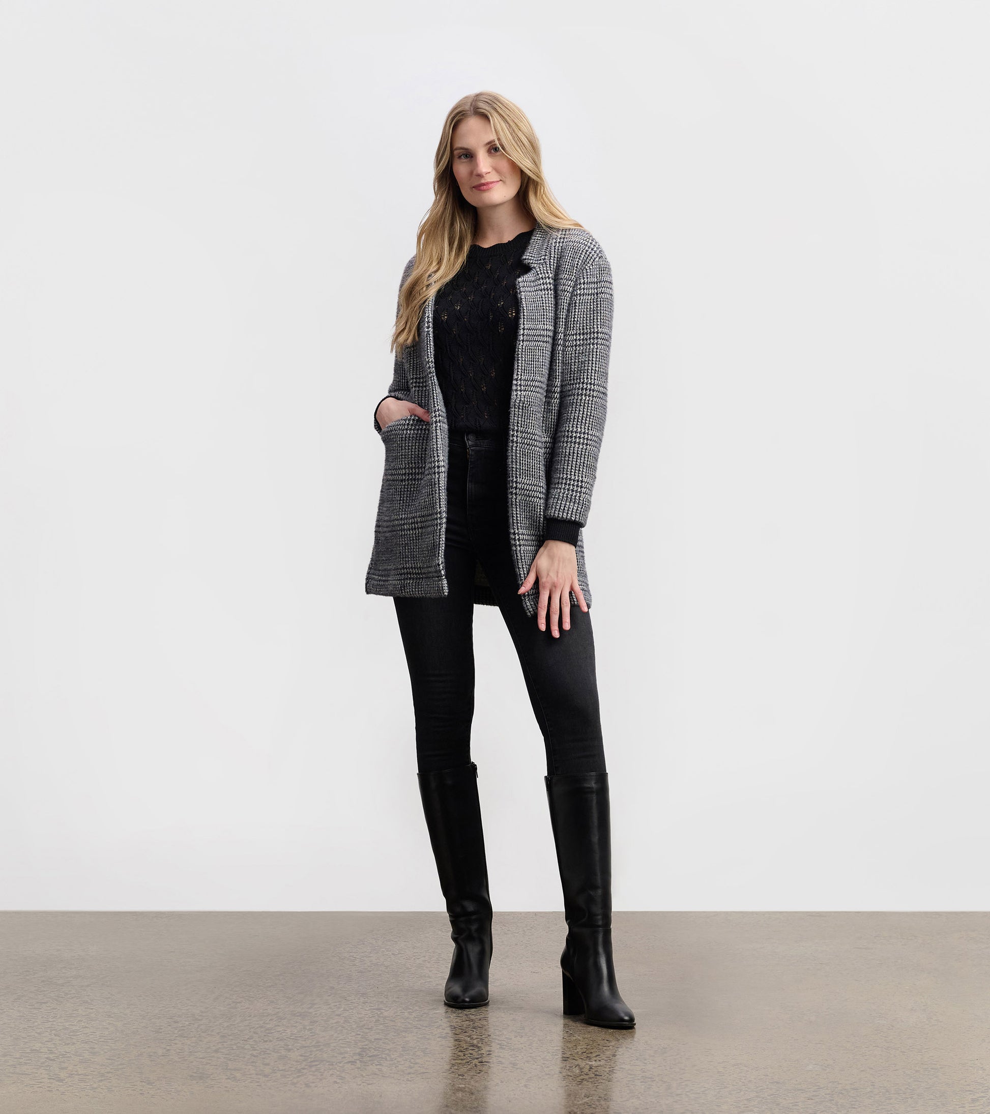 Black check open blazer with a relaxed fit, featuring pockets and a stylish collar, paired with black jeans and boots.
