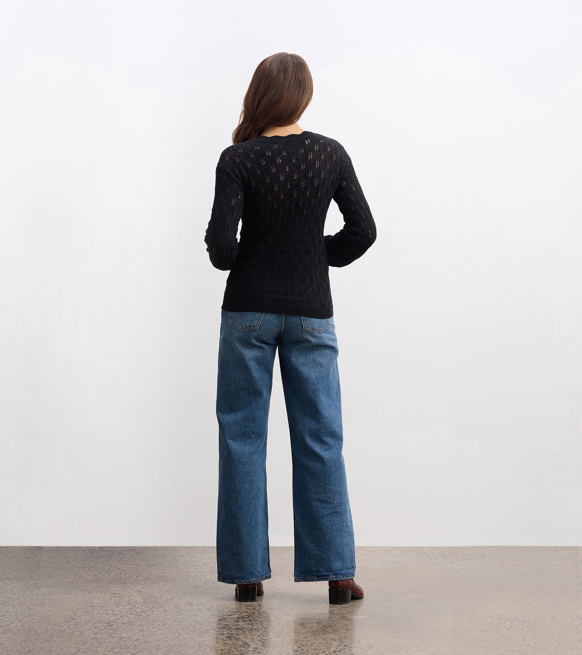 Black knitted sweater with a textured pattern, featuring long sleeves and a round neckline, viewed from the back.
