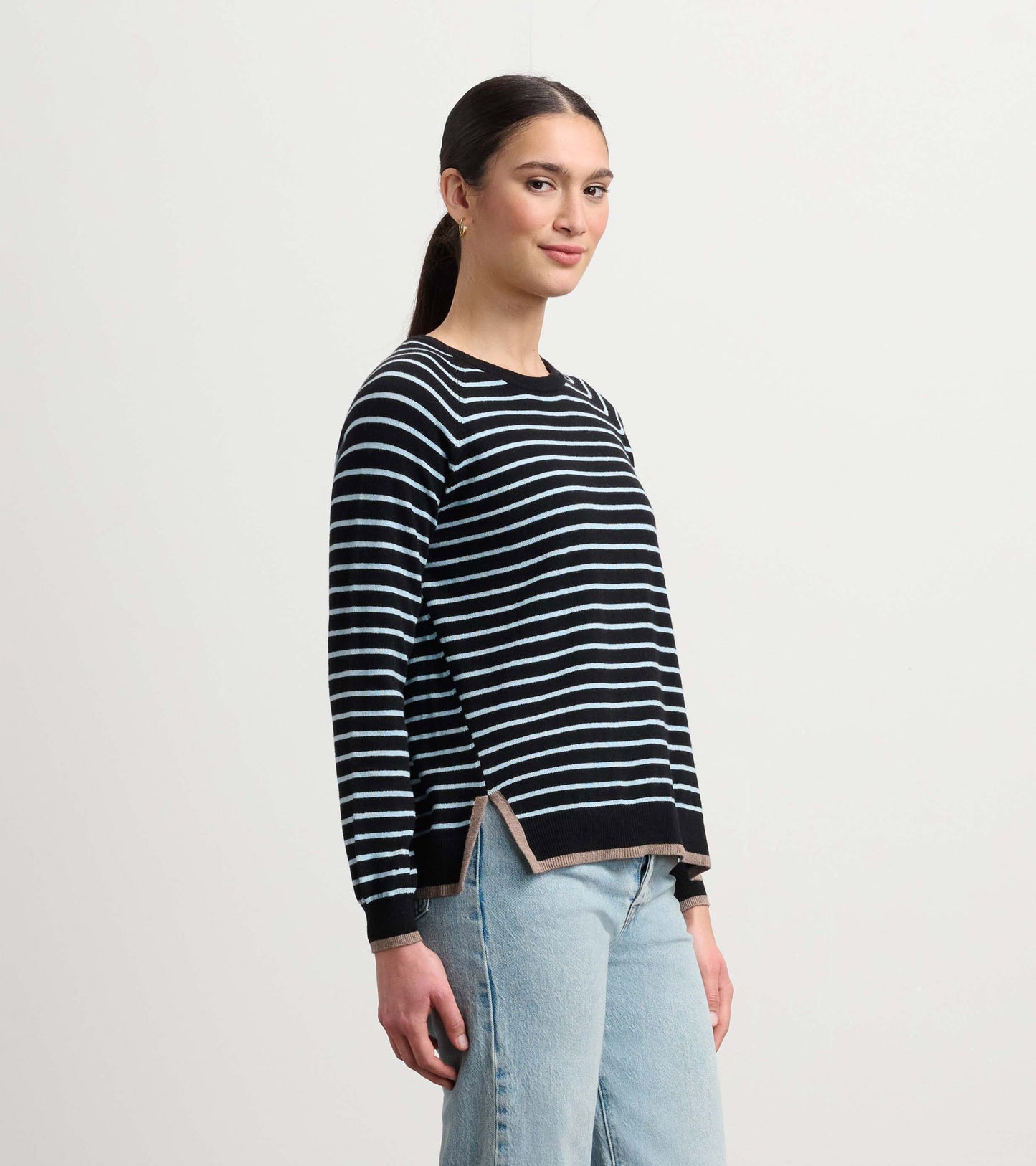 Black sweater with light blue stripes, featuring a relaxed fit and side slits, styled with light denim jeans.