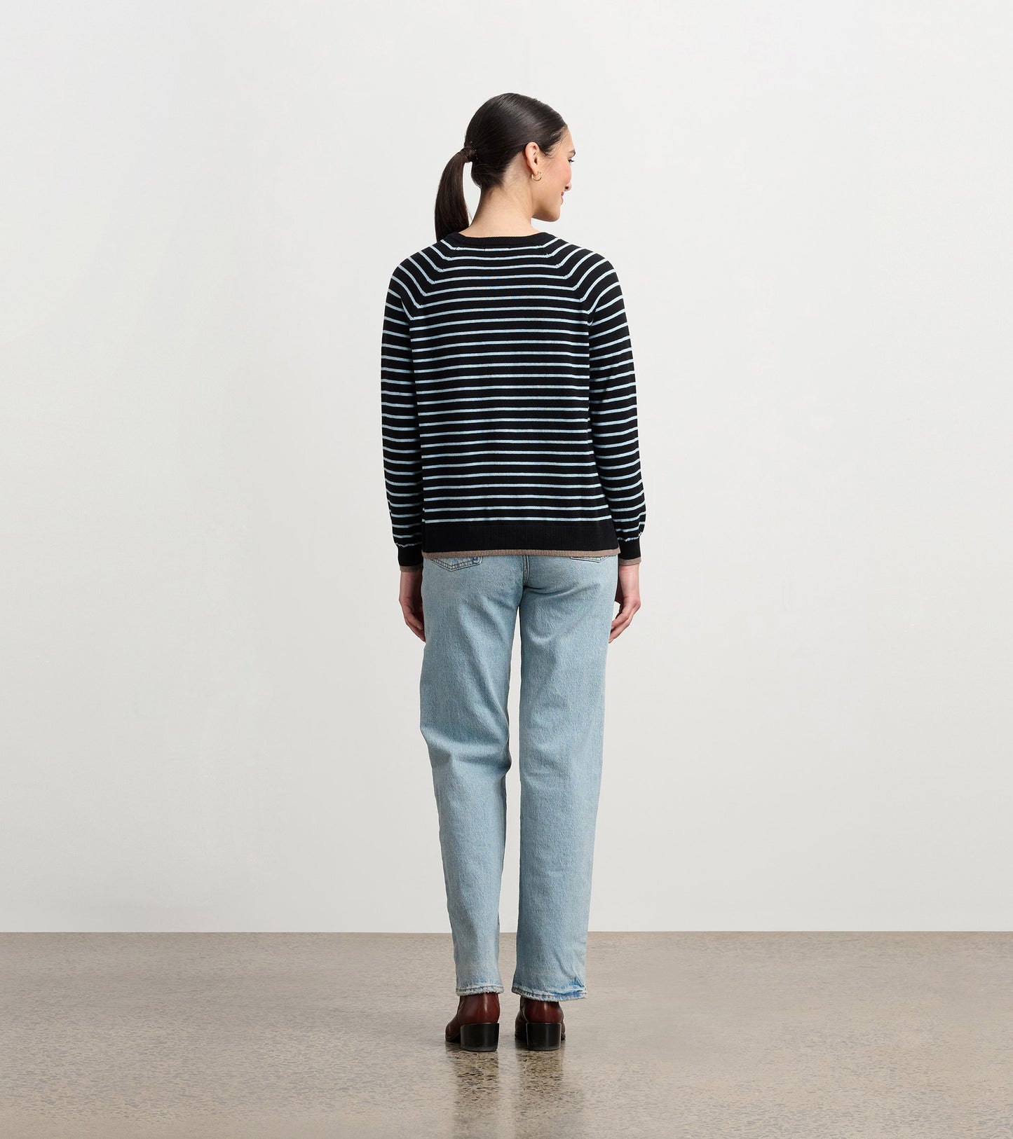 Black sweater with denim stripes, featuring a relaxed fit and ribbed cuffs, shown from the back.