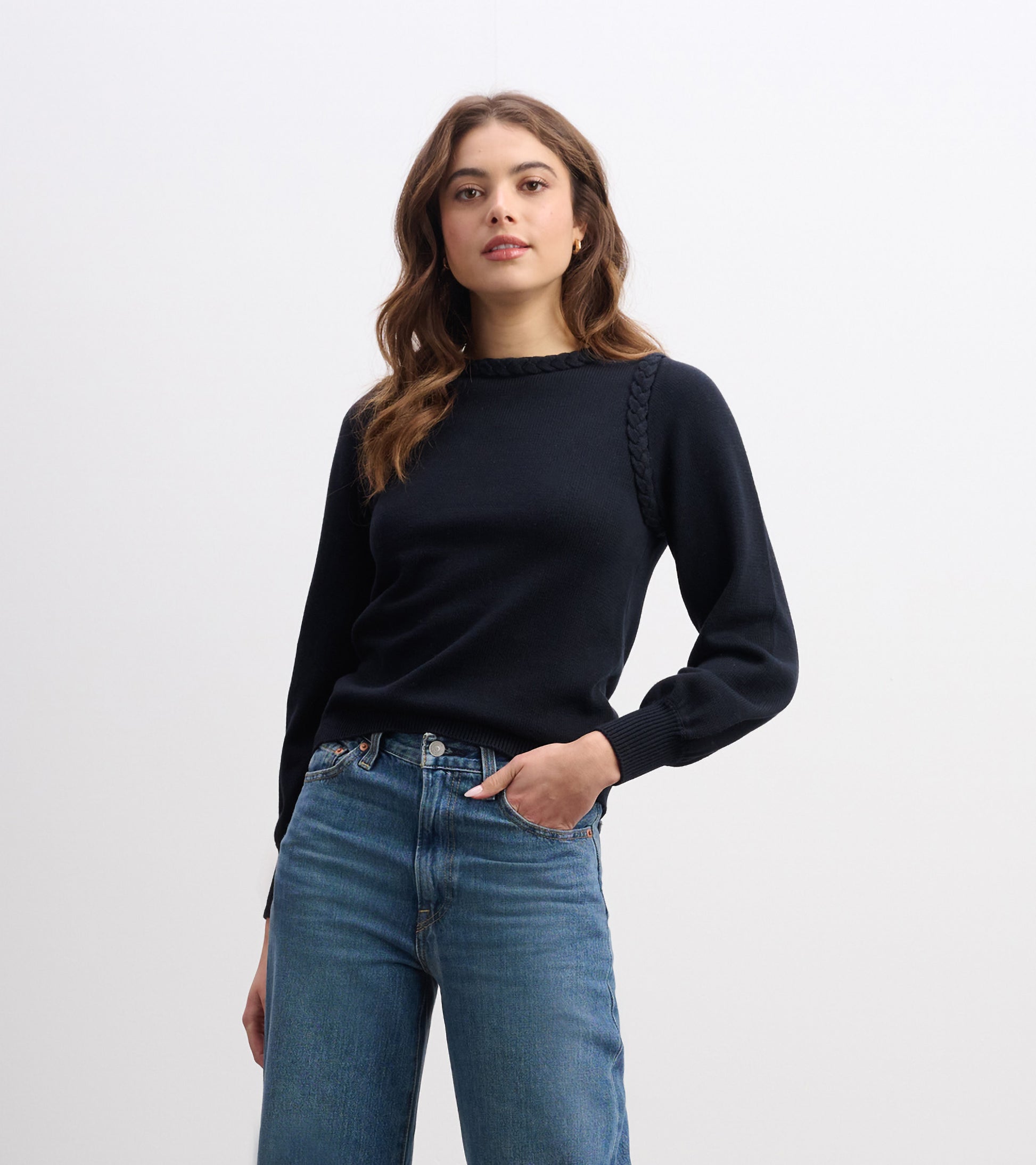Black braided sweater with long sleeves, featuring a round neckline, styled with blue jeans.