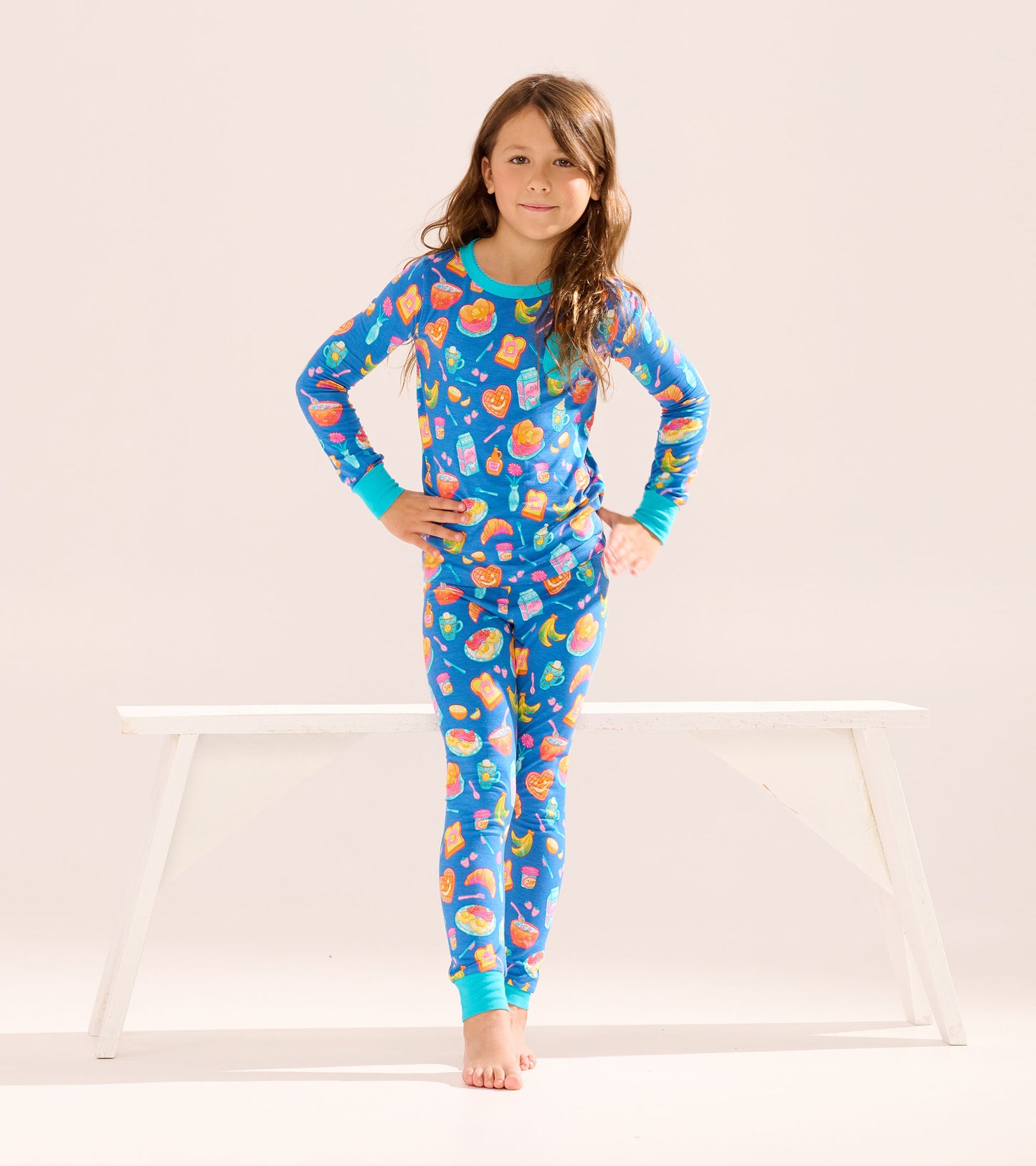Blue bamboo pajama set for girls featuring colorful breakfast food patterns, including pancakes and fruit, with long sleeves…