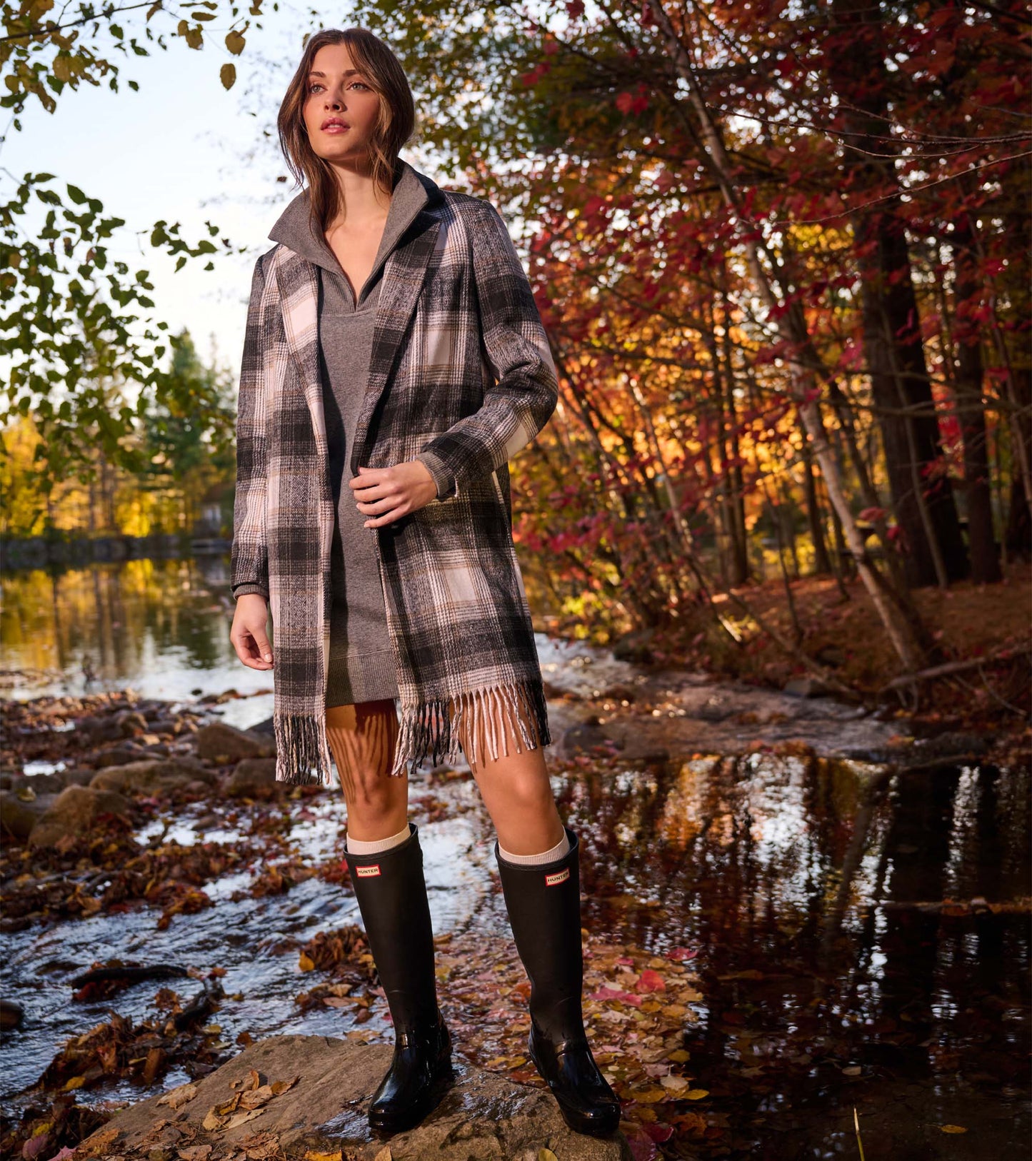 Black, taupe and white plaid fringe jacket worn open over a gray top, shown on a model outdoors.