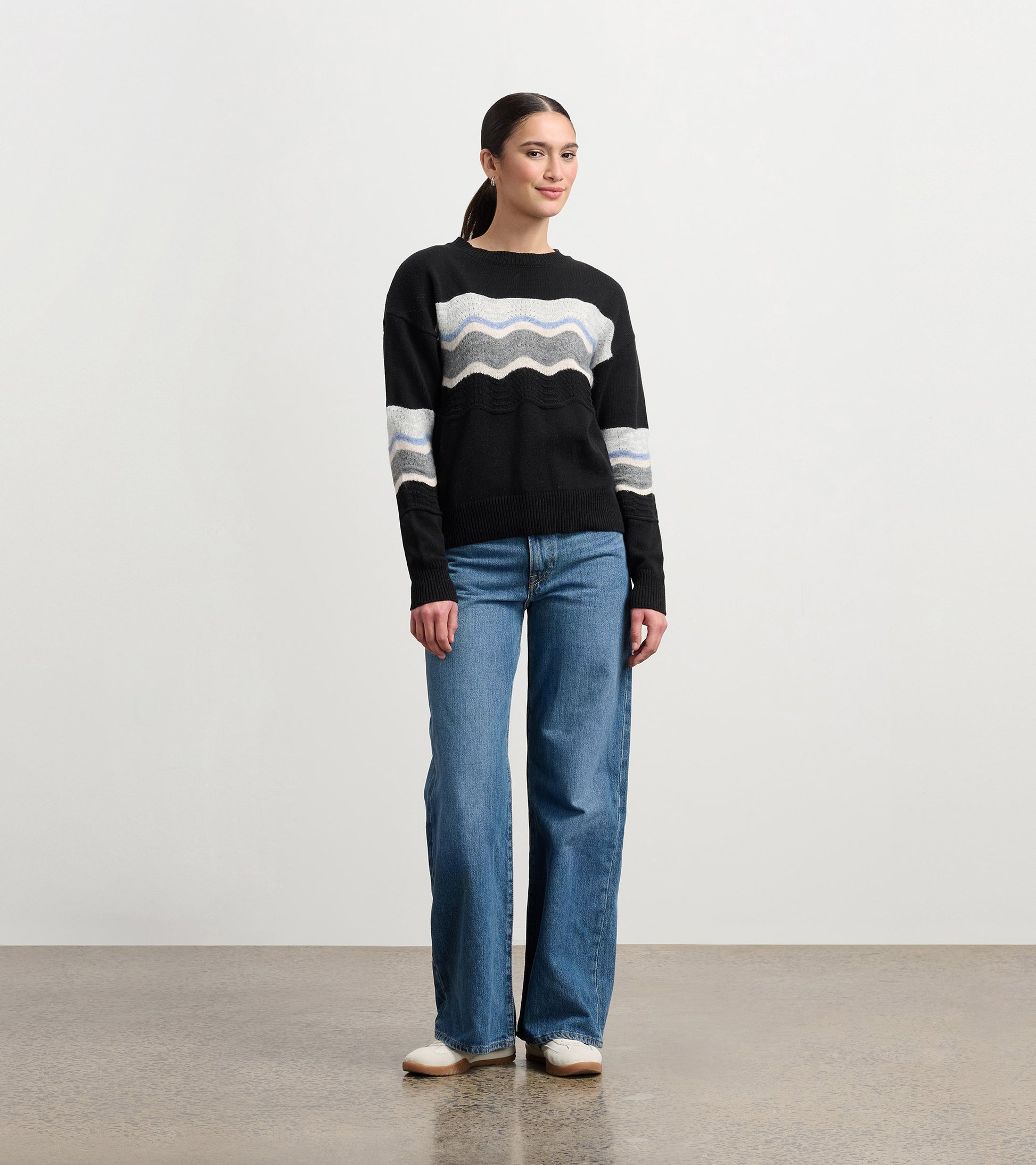 Black pointelle sweater featuring a wavy pattern in light gray and blue, styled with wide-leg jeans.