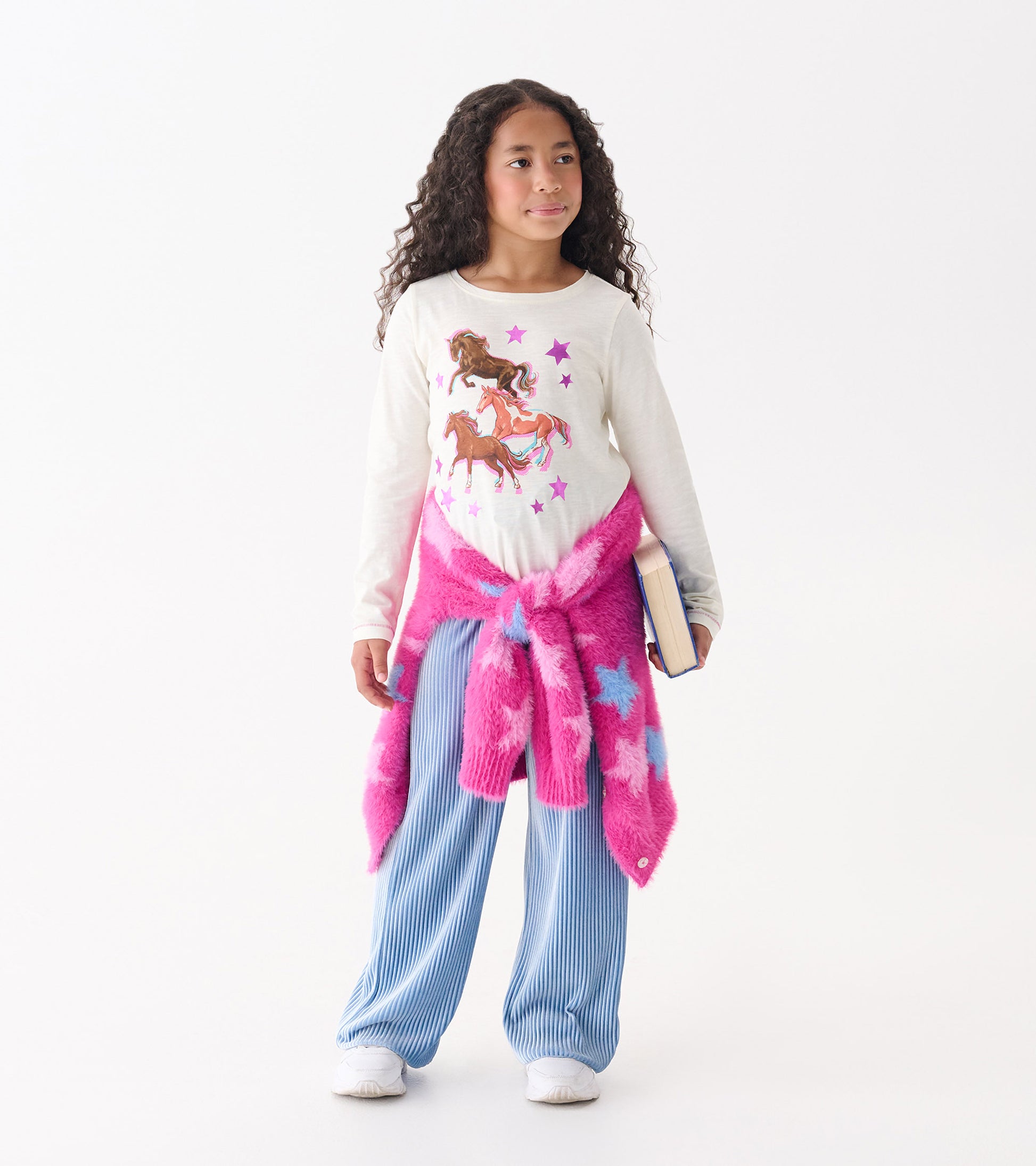 Long sleeve cream tee featuring galloping horses and stars, paired with blue striped pants and a pink star-patterned sweater.