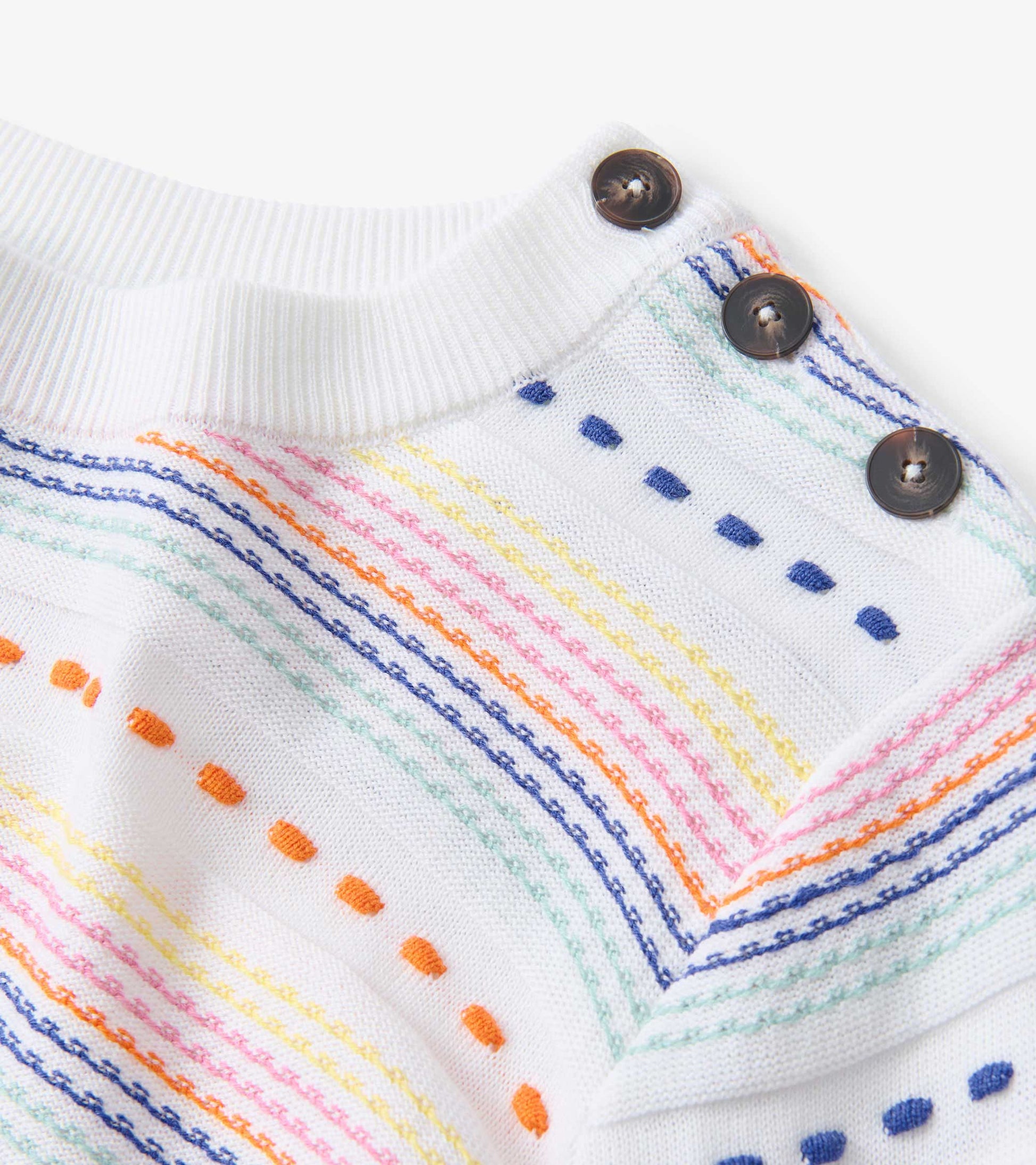 White sweater featuring colorful horizontal stripes and button detailing on the shoulder.