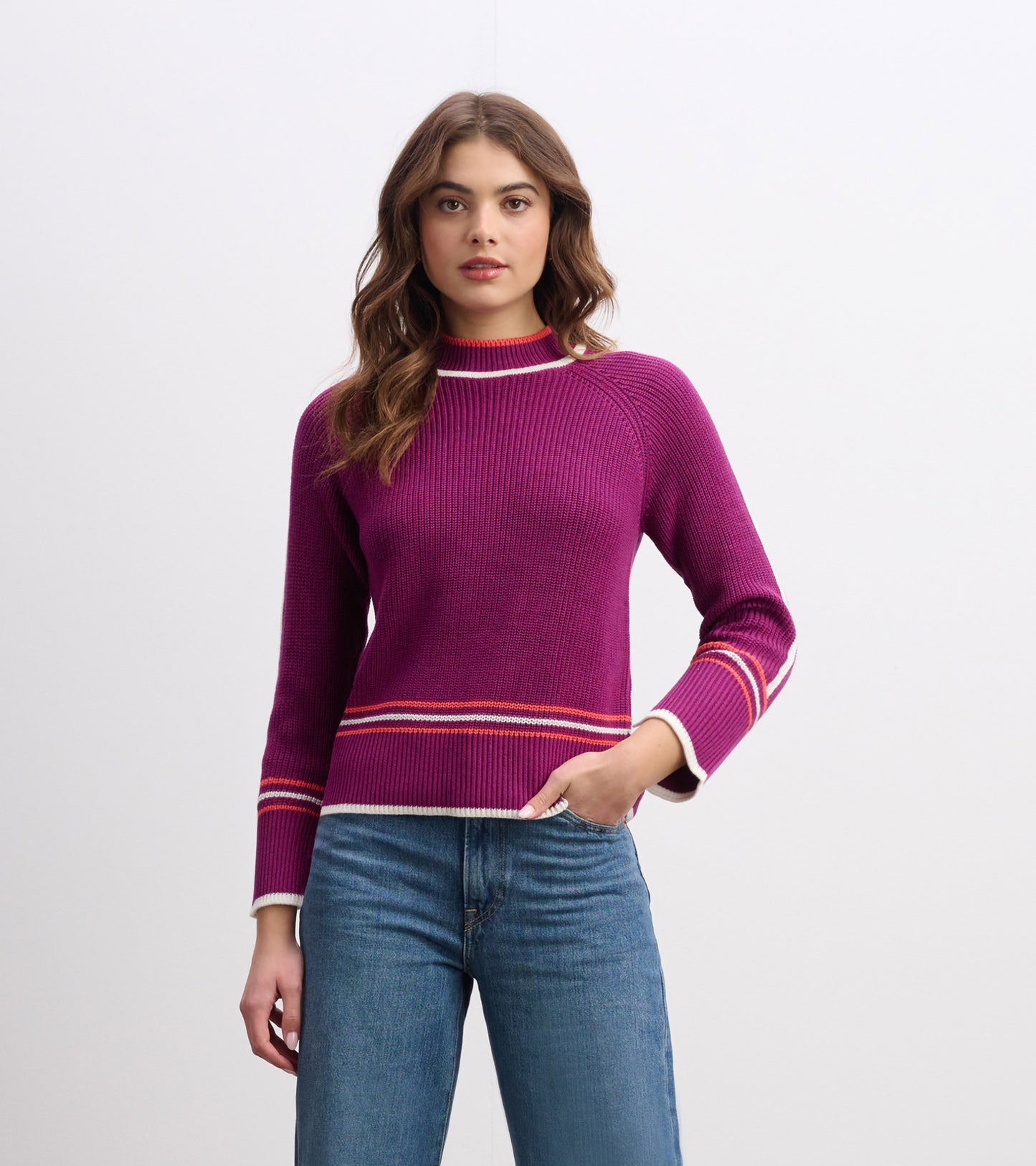 Raglan pullover in crushed grape with a ribbed texture and contrasting striped cuffs, styled with jeans.
