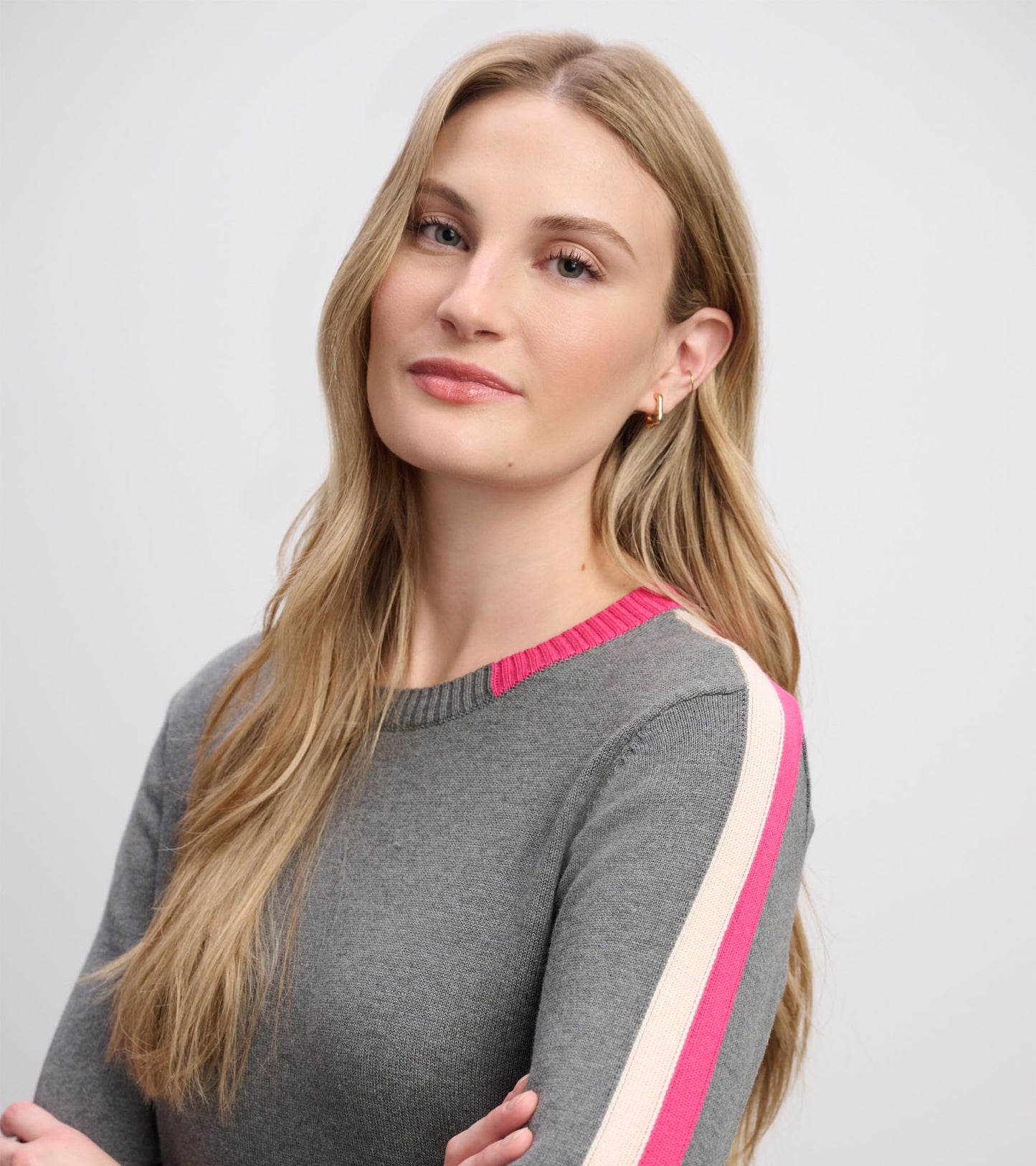Close-up of charcoal sweater dress with ribbed neckline and pink and cream stripe trim on the shoulder
