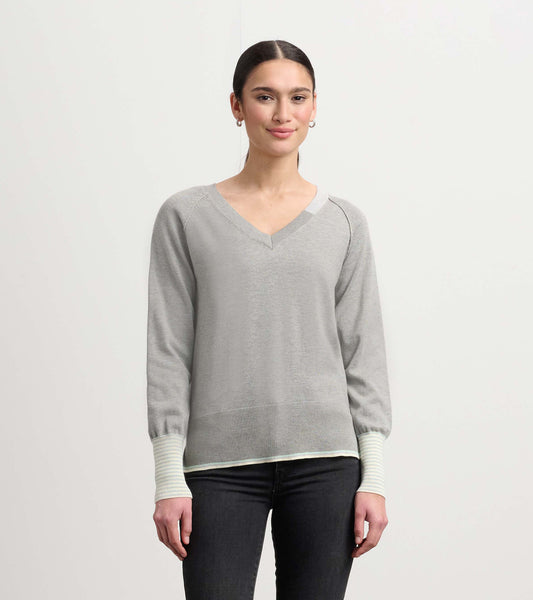 Charcoal melange V-neck sweater with long sleeves and striped cuffs, styled with dark jeans.