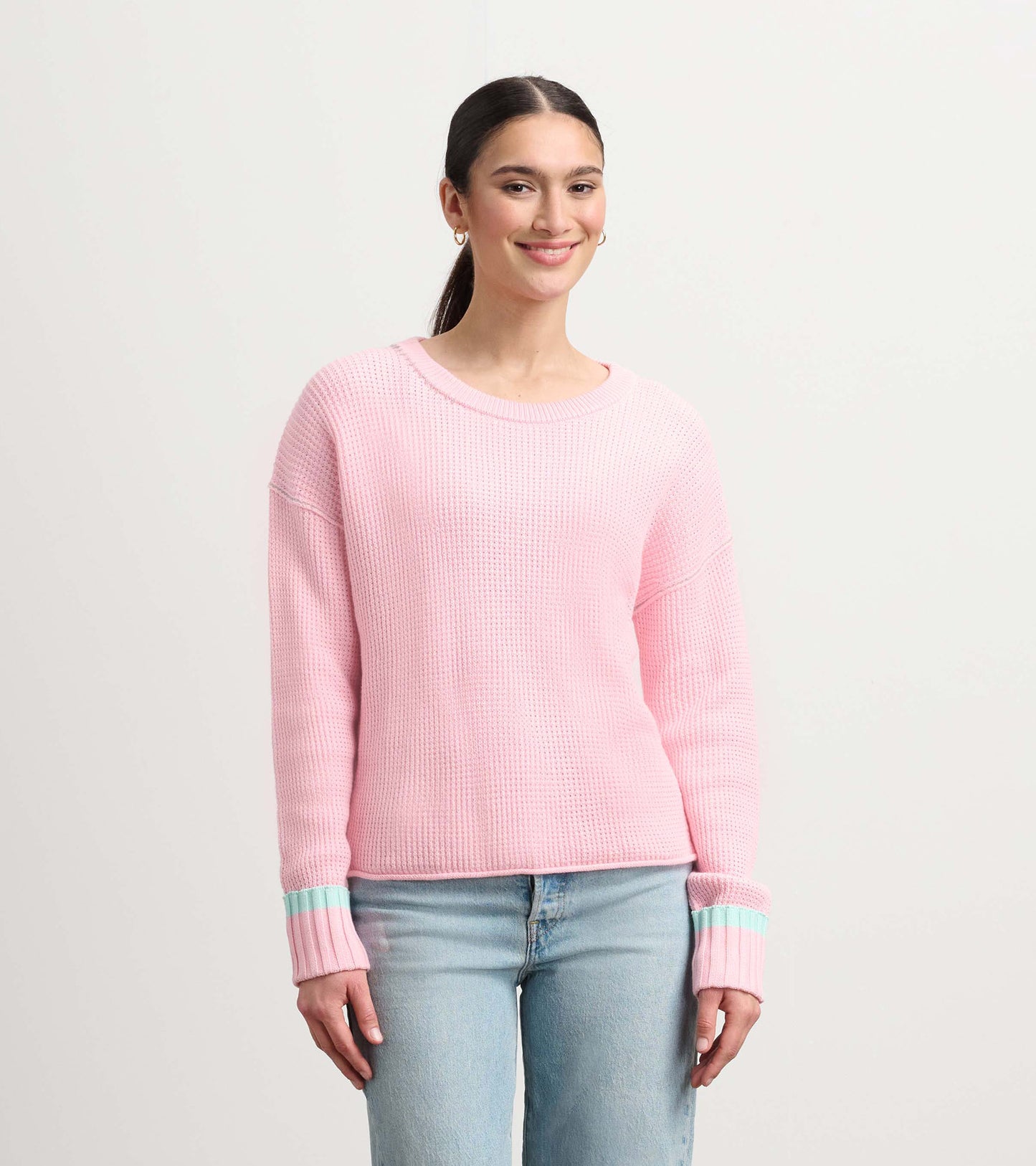 Fuchsia pink waffle knit sweater with long sleeves and contrasting mint green stripes on the cuffs.