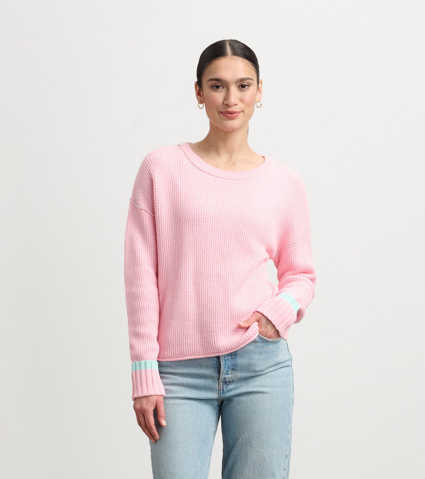 Fuchsia pink waffle knit sweater with mint green striped cuffs, featuring a relaxed fit and round neckline.