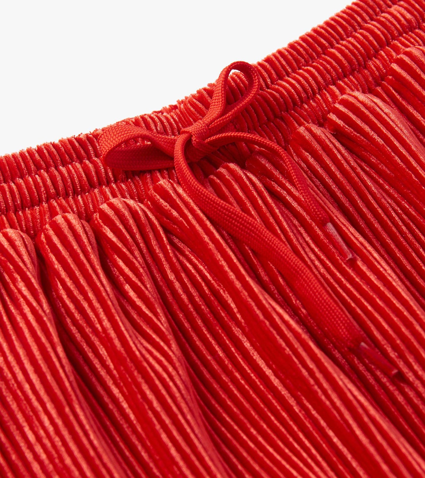 Red pleated velour skirt with an elastic waistband and bow detail, suitable for girls.