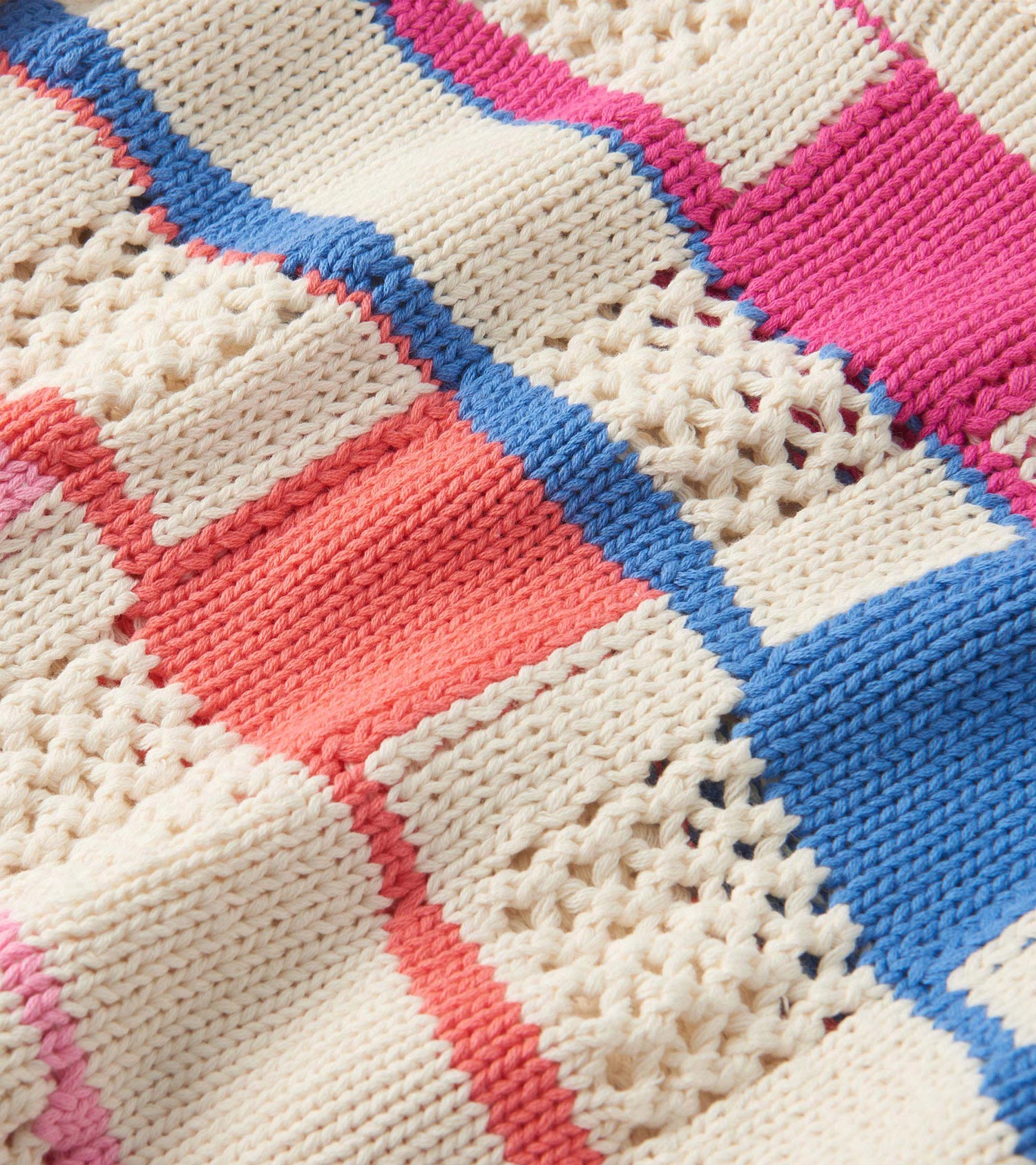 Knit sweater featuring a mix of colorful blocks in pink, blue, coral, and cream with textured patterns.