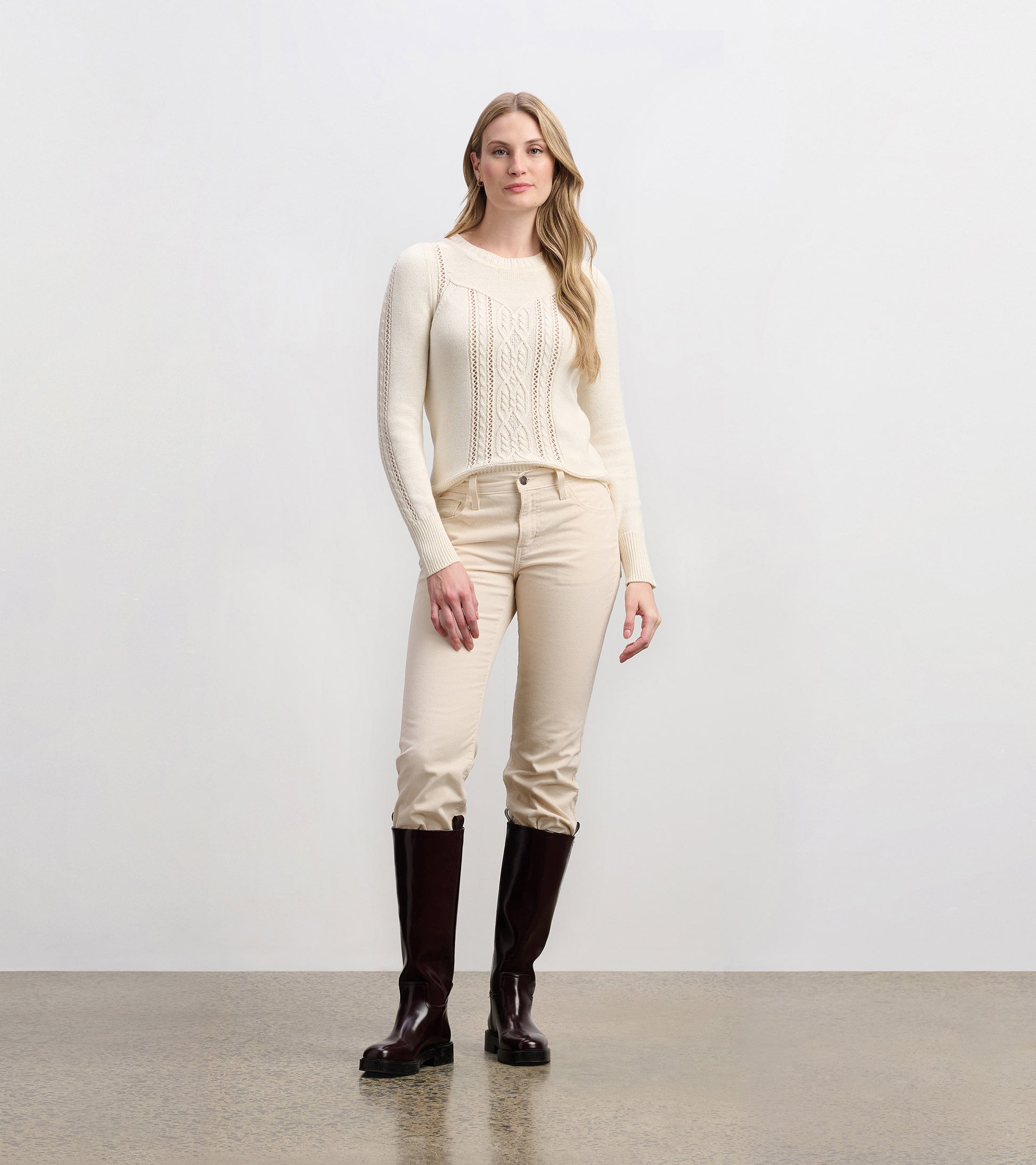 Cream sweater with a textured cable knit pattern, featuring long sleeves and a relaxed fit.