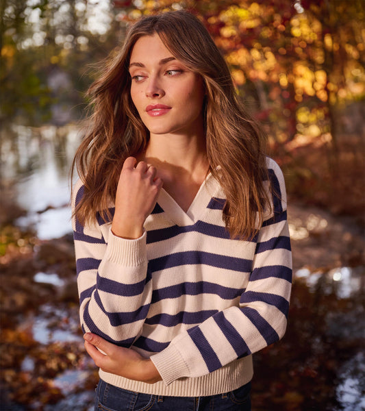 Nautical striped sweater in cream and navy, featuring a V-neck and long sleeves, styled with dark jeans.