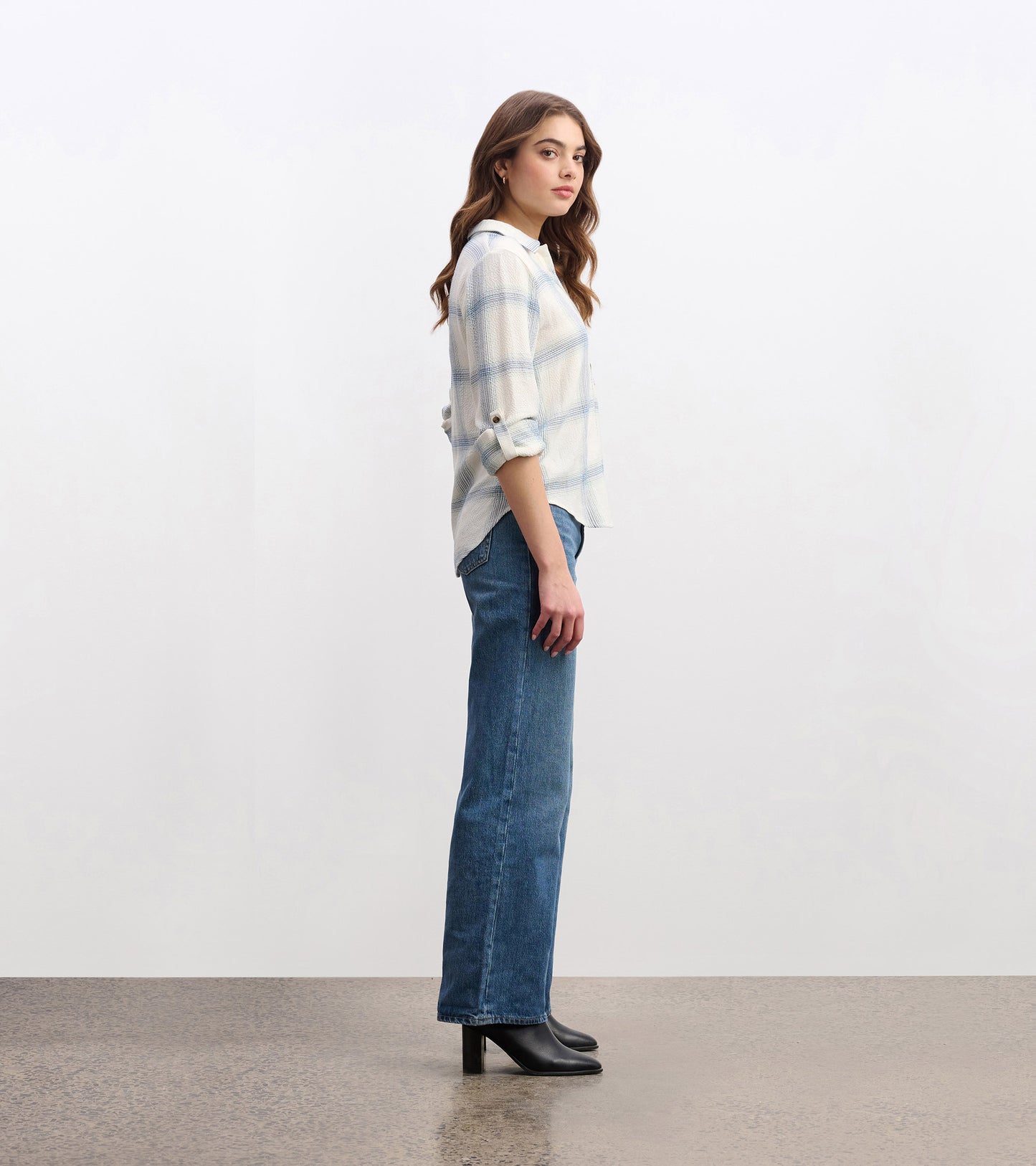 Turquoise plaid button-down shirt with rolled sleeves, styled with high-waisted jeans and heeled boots.