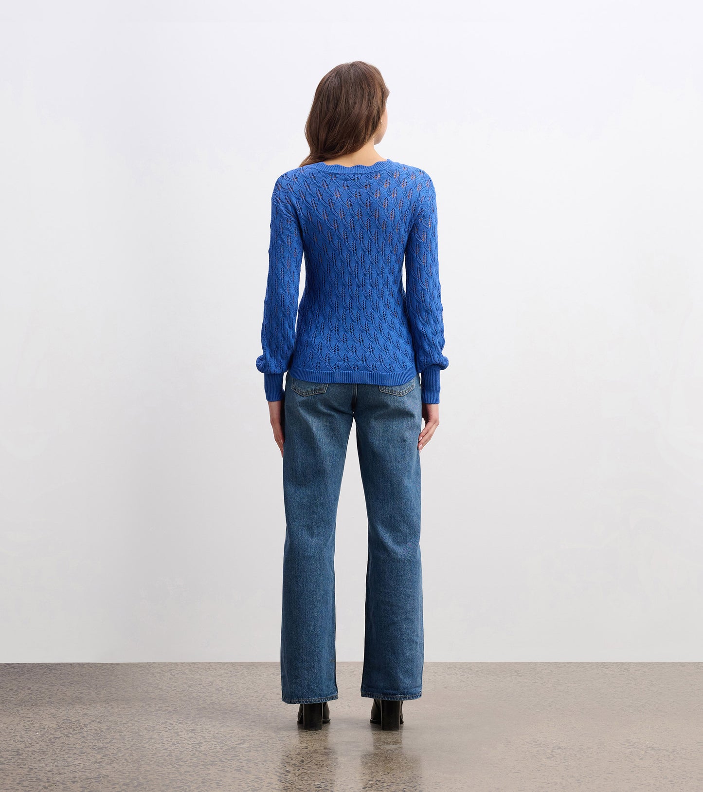 Denim blue knitted sweater with a textured pattern, featuring long sleeves and a crew neckline, viewed from the back.