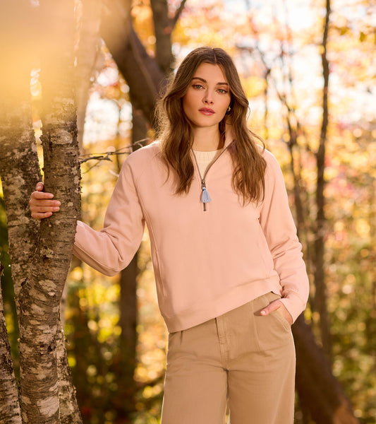 Pink mock neck pullover with a half-zip front and long sleeves, styled with fitted jeans.