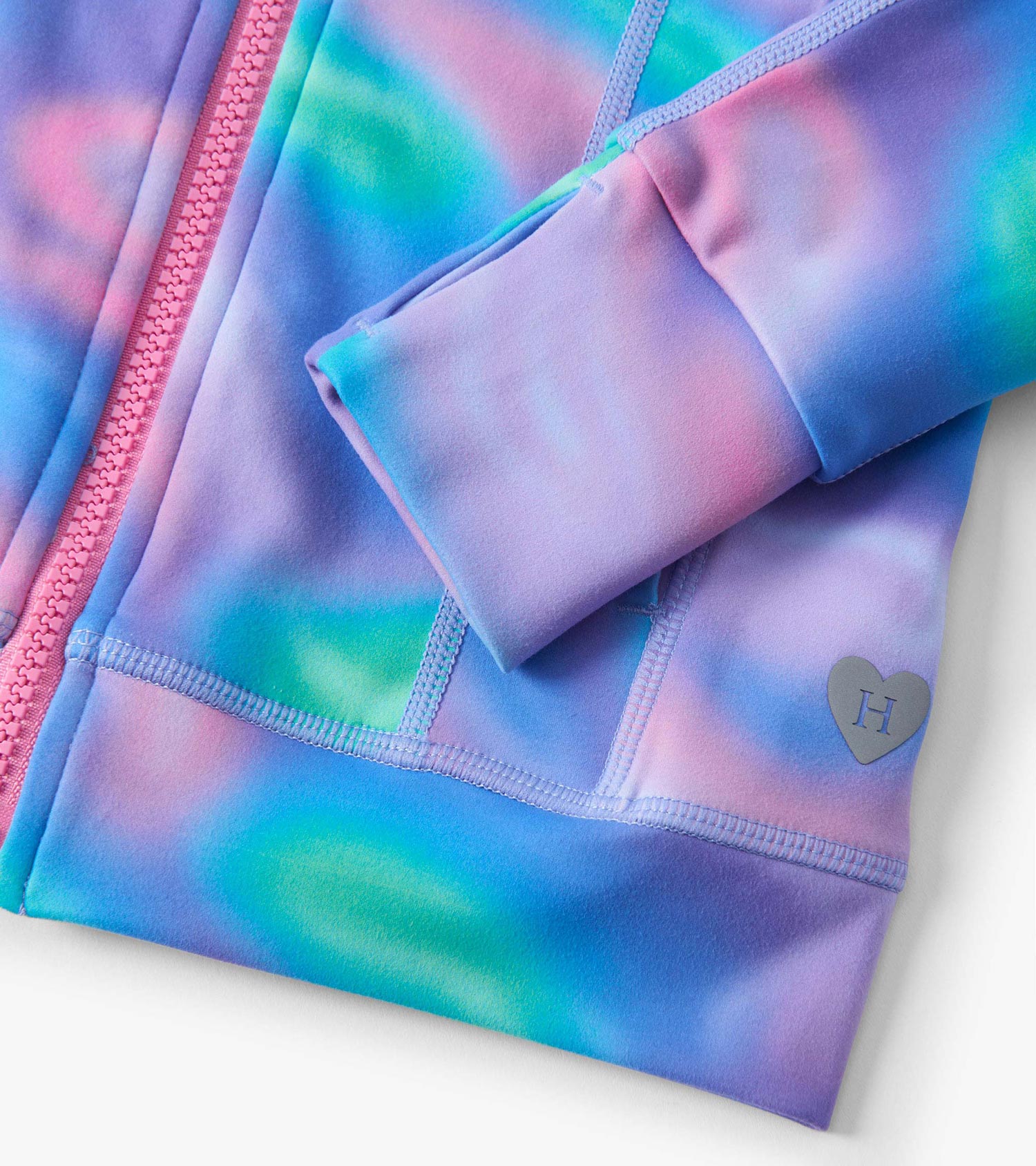 Colorful tie-dye active jacket in shades of blue, pink, and green with a zip closure and heart logo detail.