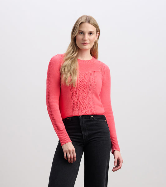 Neon melon sweater with a textured cable knit pattern, featuring long sleeves and a round neckline, styled with black jeans.