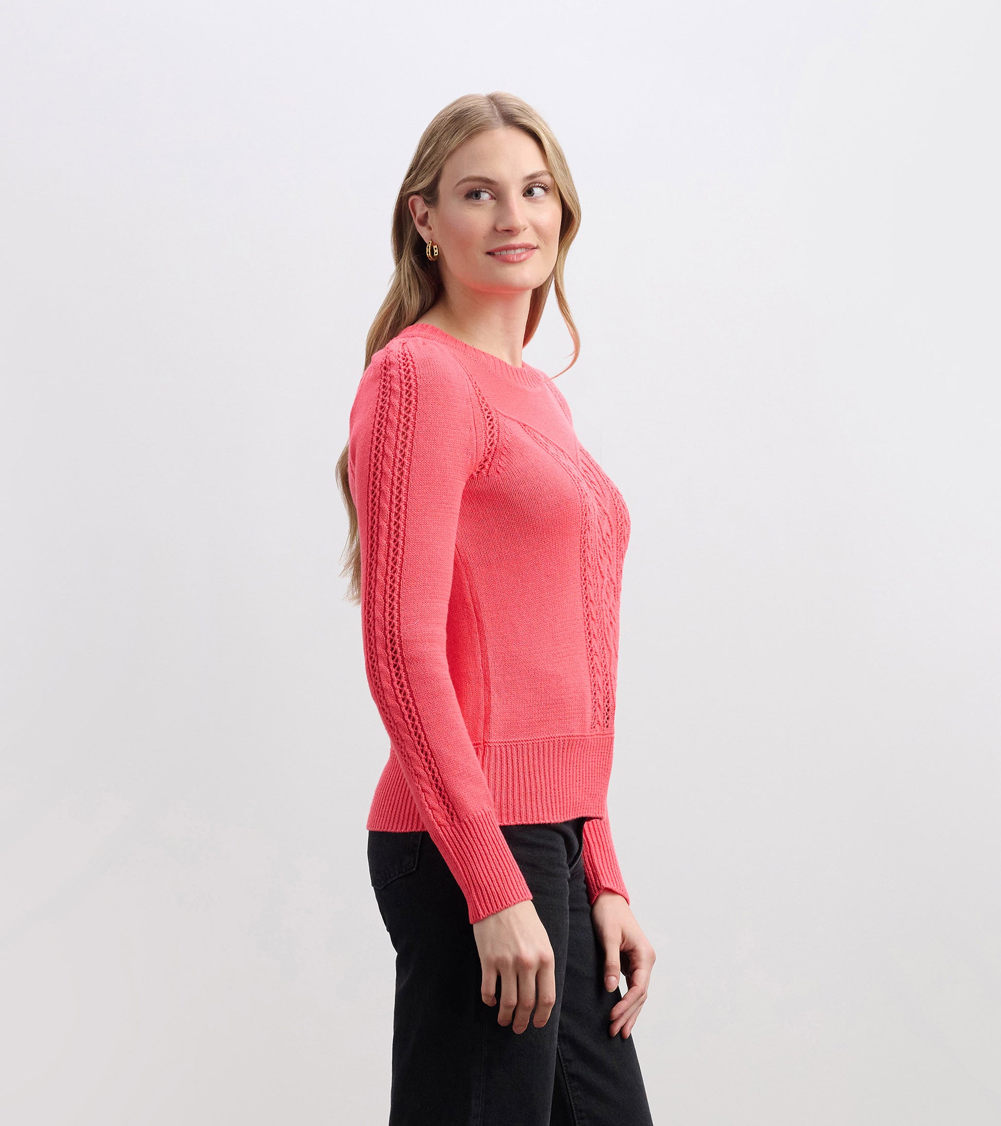 Neon melon sweater with a fitted silhouette, textured detailing on sleeves, and ribbed hem, worn with black pants.
