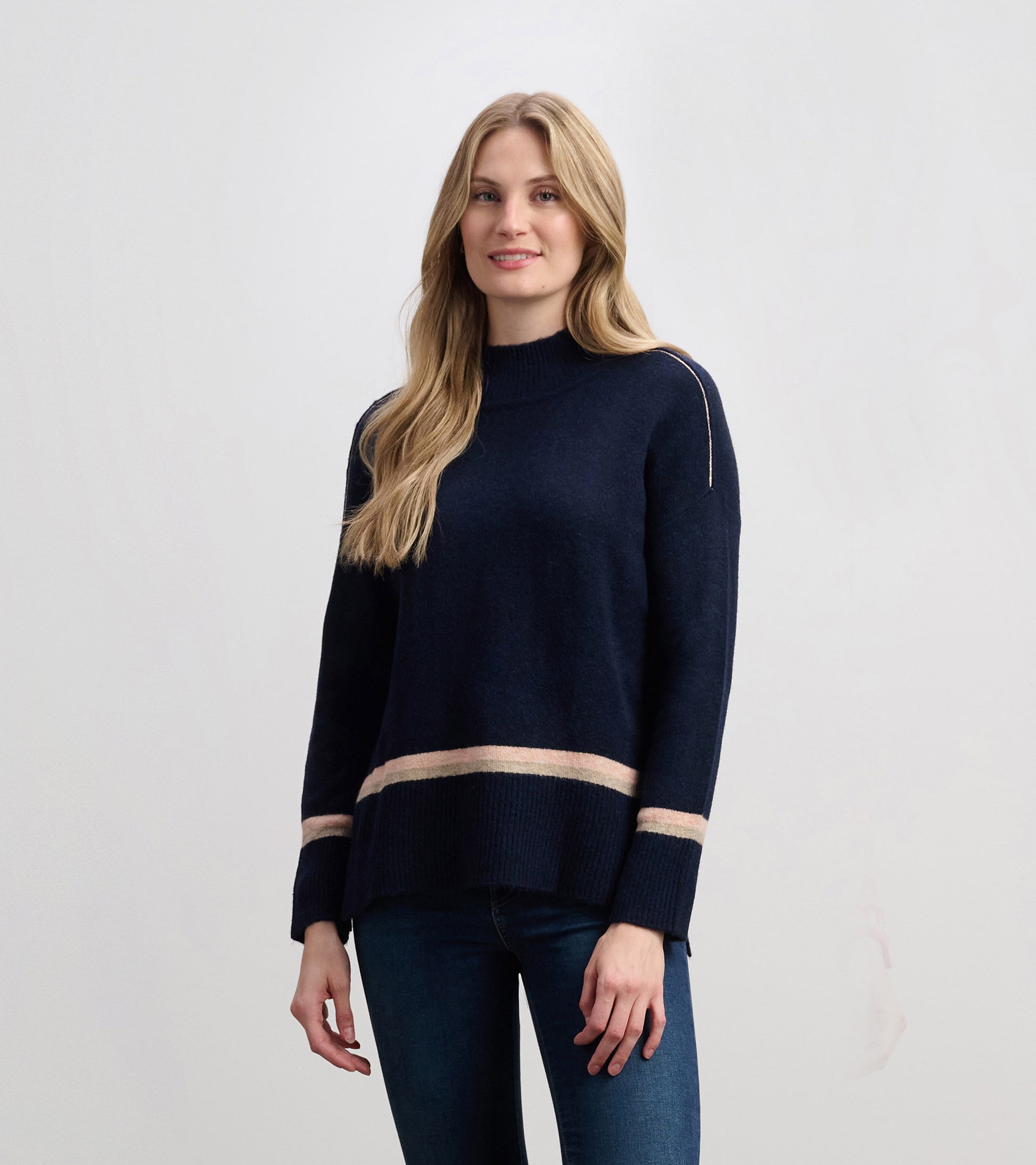Navy mock neck sweater featuring a striped hem, long sleeves, and a relaxed fit, styled with jeans.