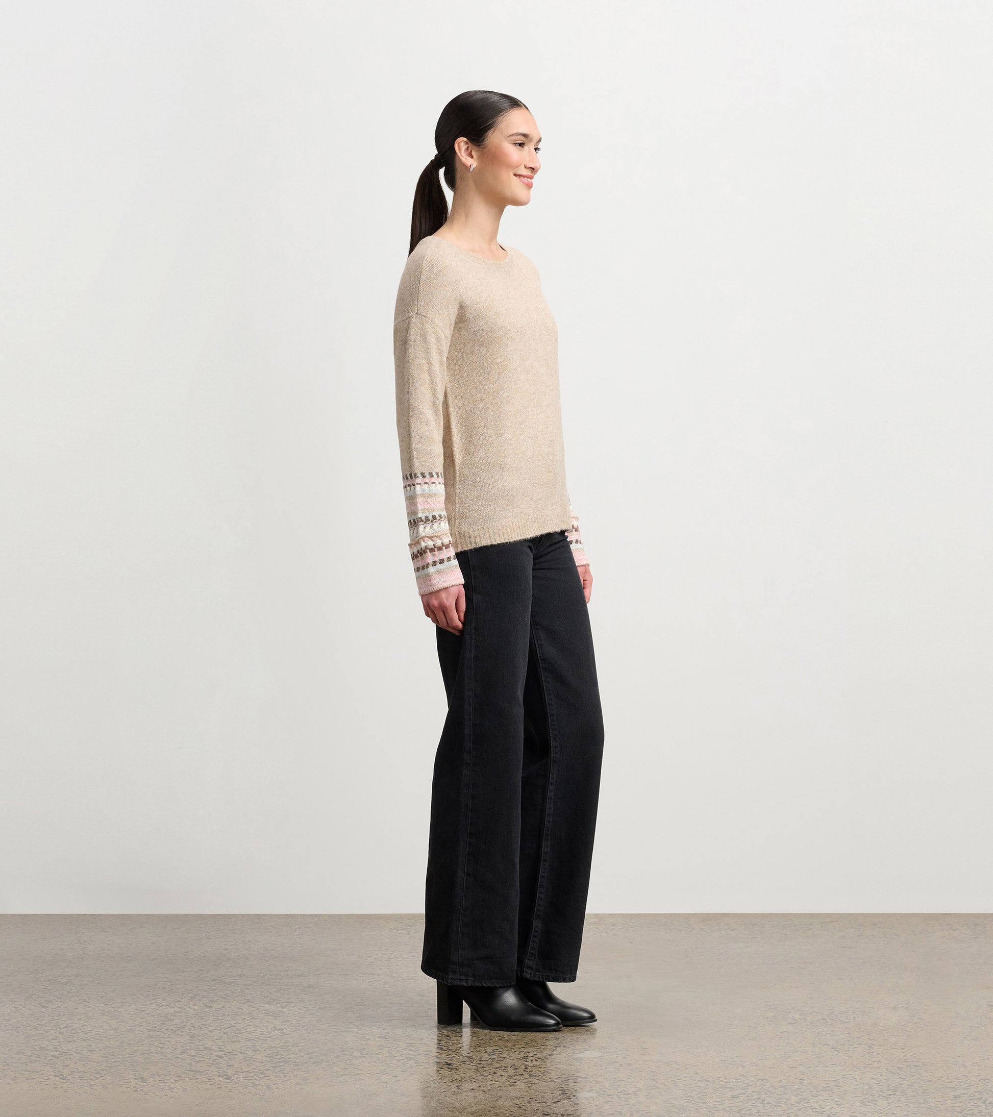 Oatmeal melange sweater with patterned cuffs, featuring a relaxed fit and long sleeves, styled with black wide-leg pants.