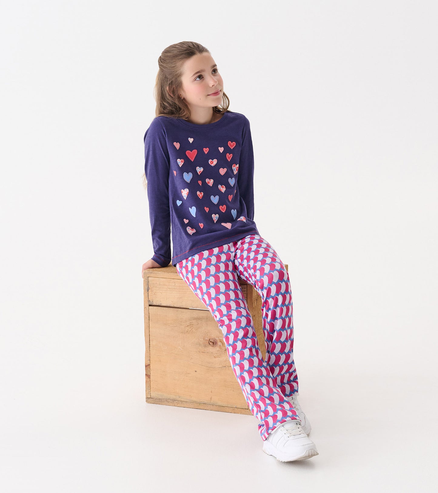 Long sleeve navy tee with colorful heart graphics paired with pink and white patterned pants.