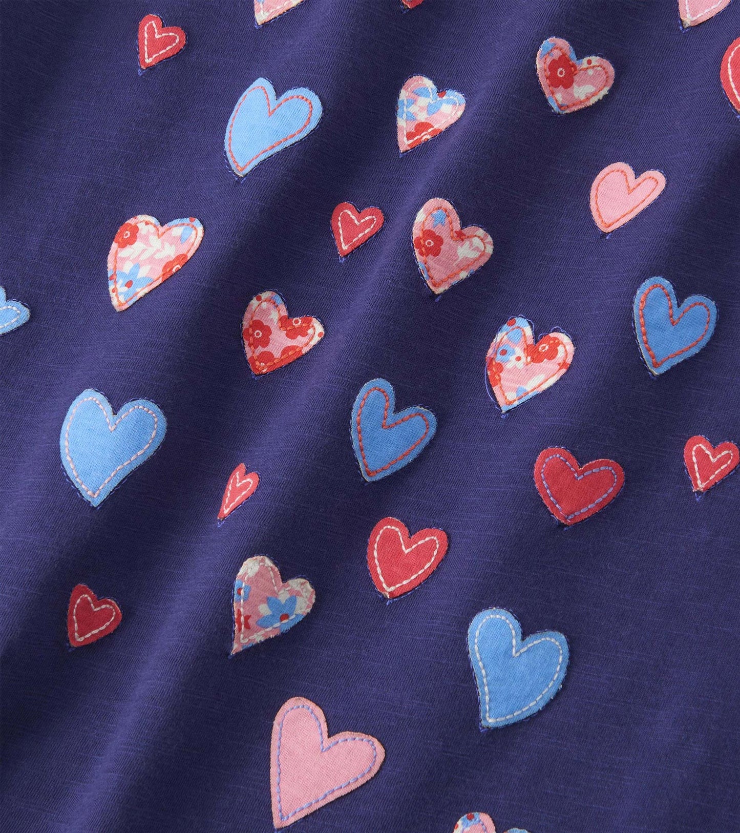 Navy long sleeve tee featuring colorful heart patterns in various shades and floral designs.