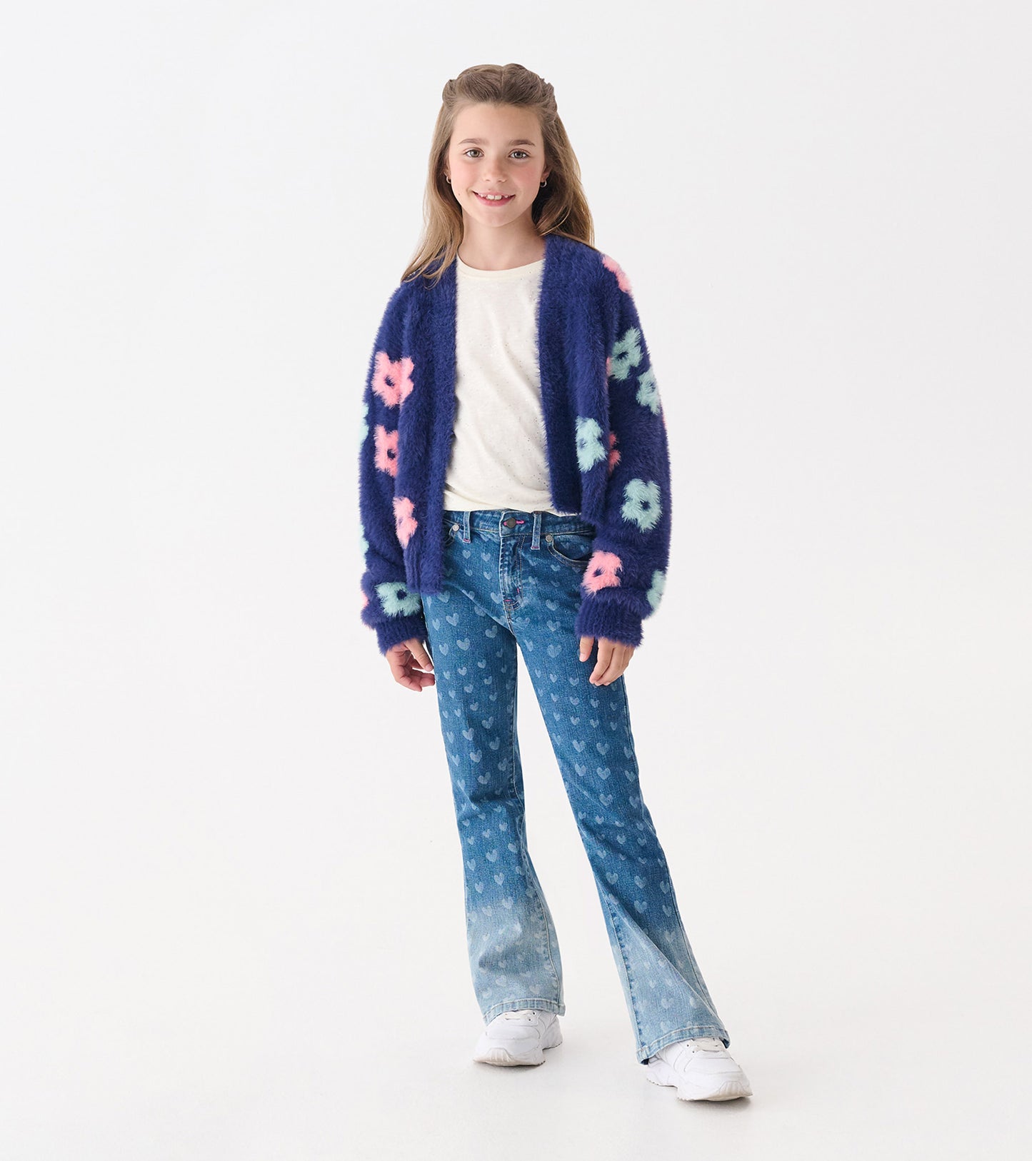 Navy open cardigan with large pink and mint flowers, worn over a white shirt and paired with flared jeans.