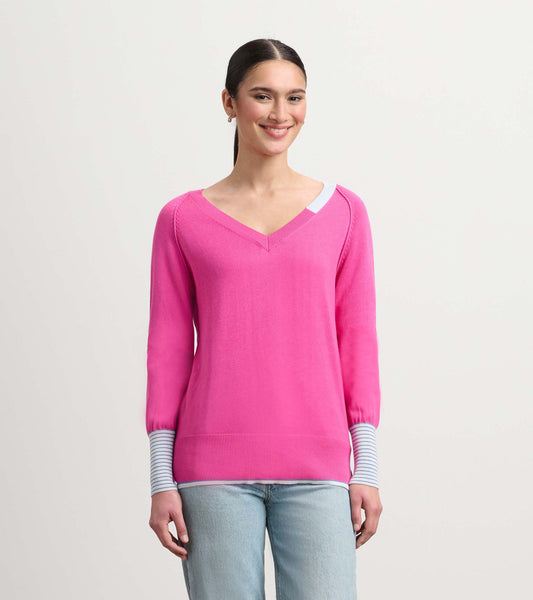 V-neck pink sweater with long sleeves featuring striped cuffs, styled casually with light blue jeans.