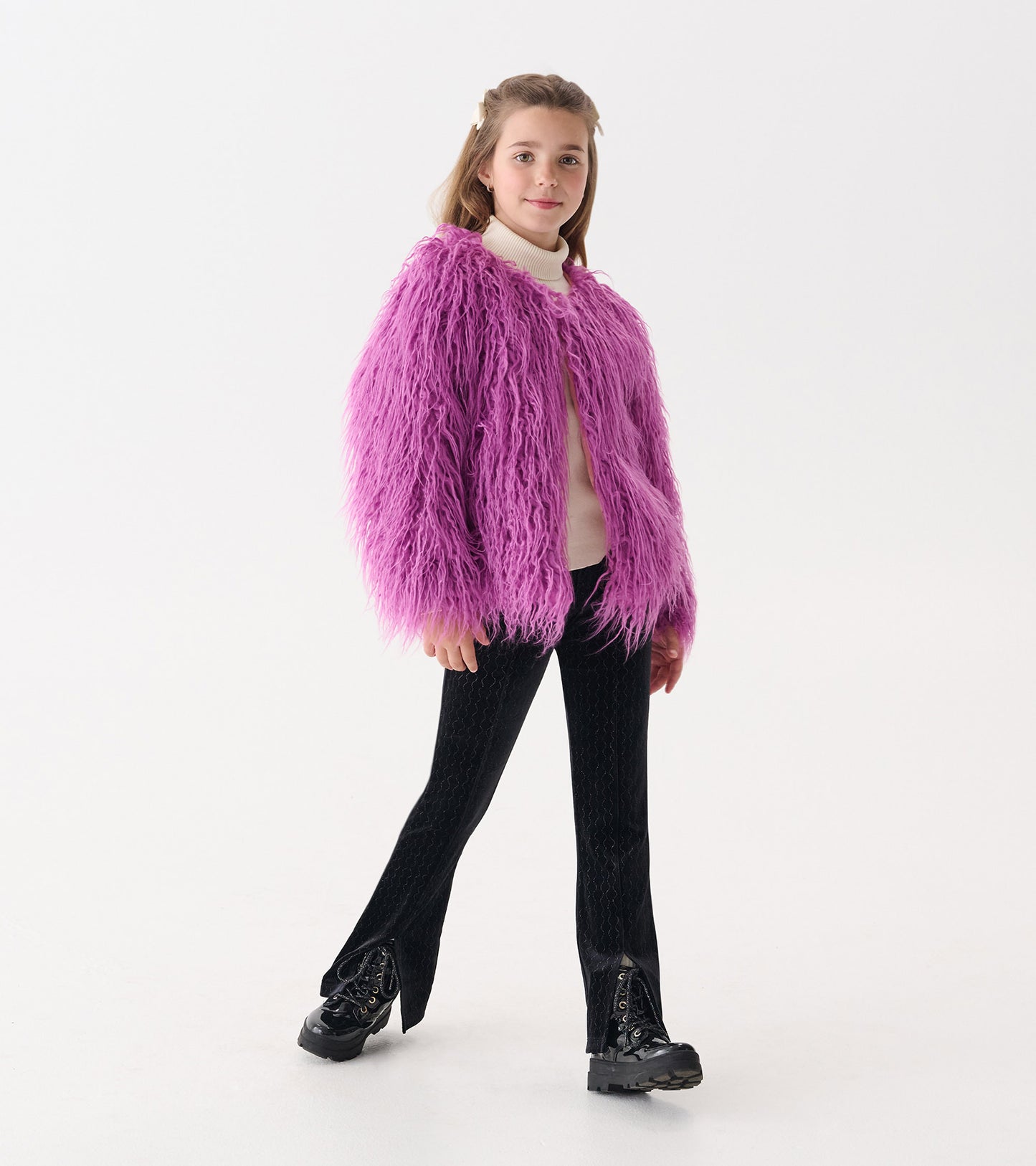 Radiant orchid faux fur topper with long sleeves, worn over a light sweater and paired with black pants and boots.