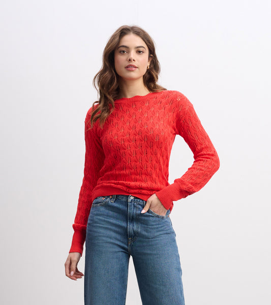 Ruby red knitted sweater with a textured pattern and long sleeves, styled with high-waisted jeans.