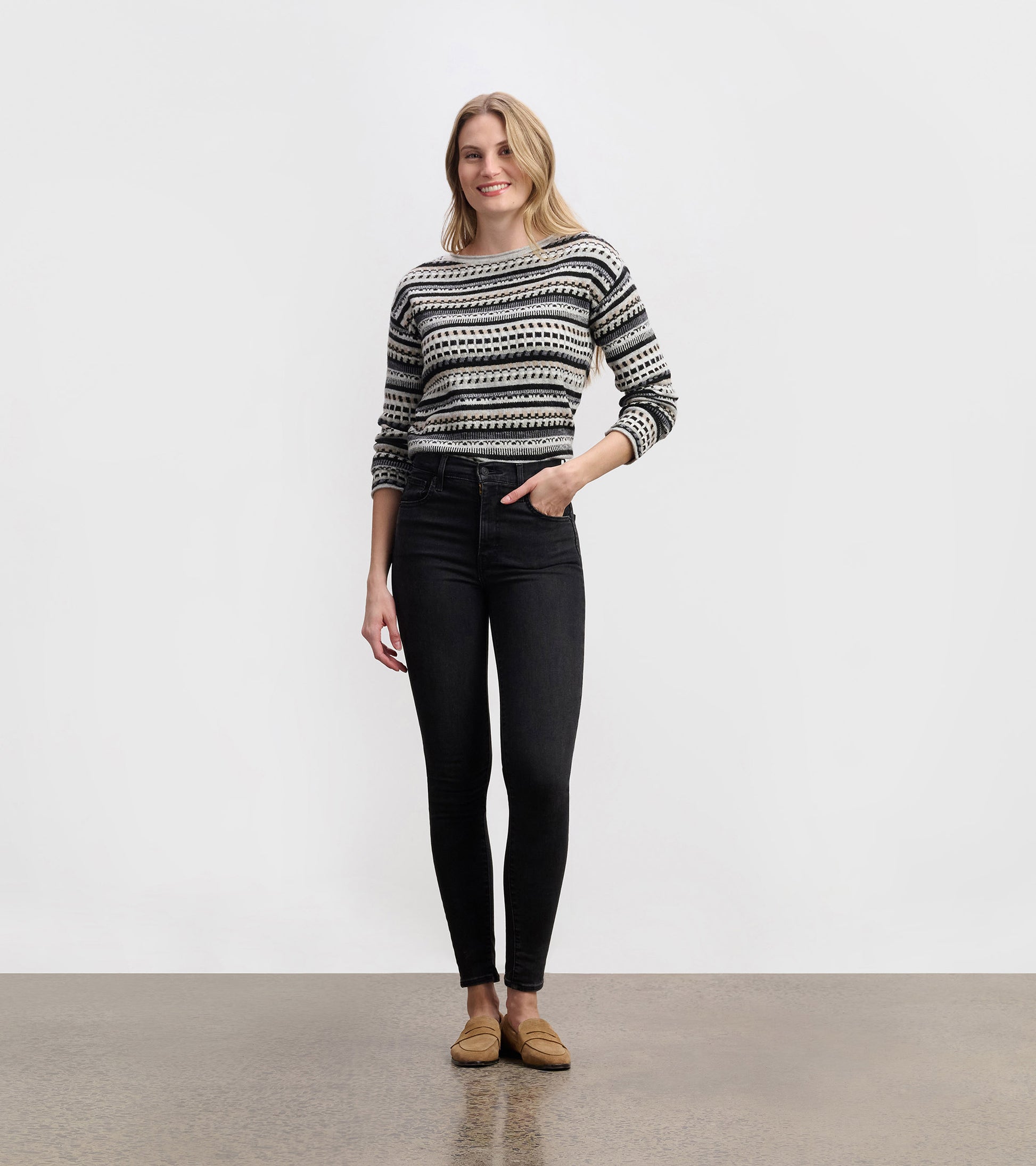 Stone grey sweater with a striped pattern, round neckline, and long sleeves, paired with black jeans.