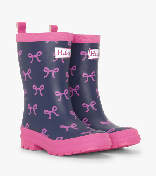 Navy rain boots with pink bow patterns and pink soles, featuring pull tabs for easy wear.