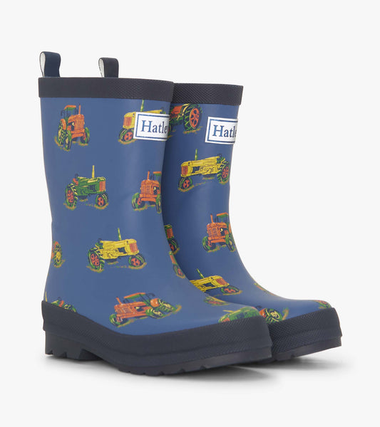 Matte blue rain boots featuring colorful tractor patterns, designed for boys with pull tabs for easy wear.