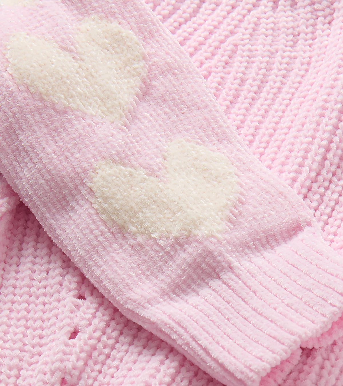 Close-up of pink knit sweater sleeve with cream heart pattern