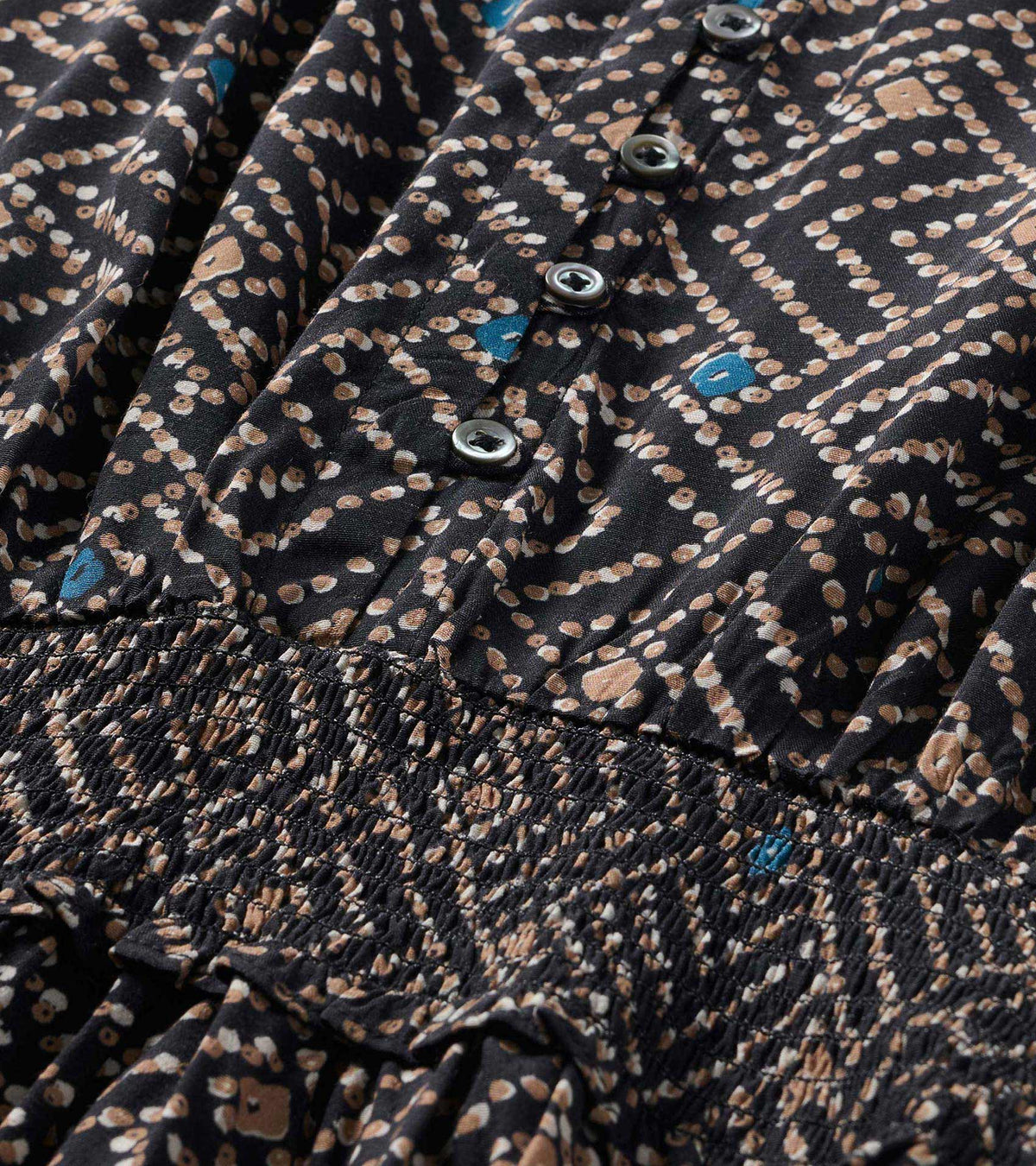 Close-up of the broken ikat print dress with front buttons and smocked waistband detail