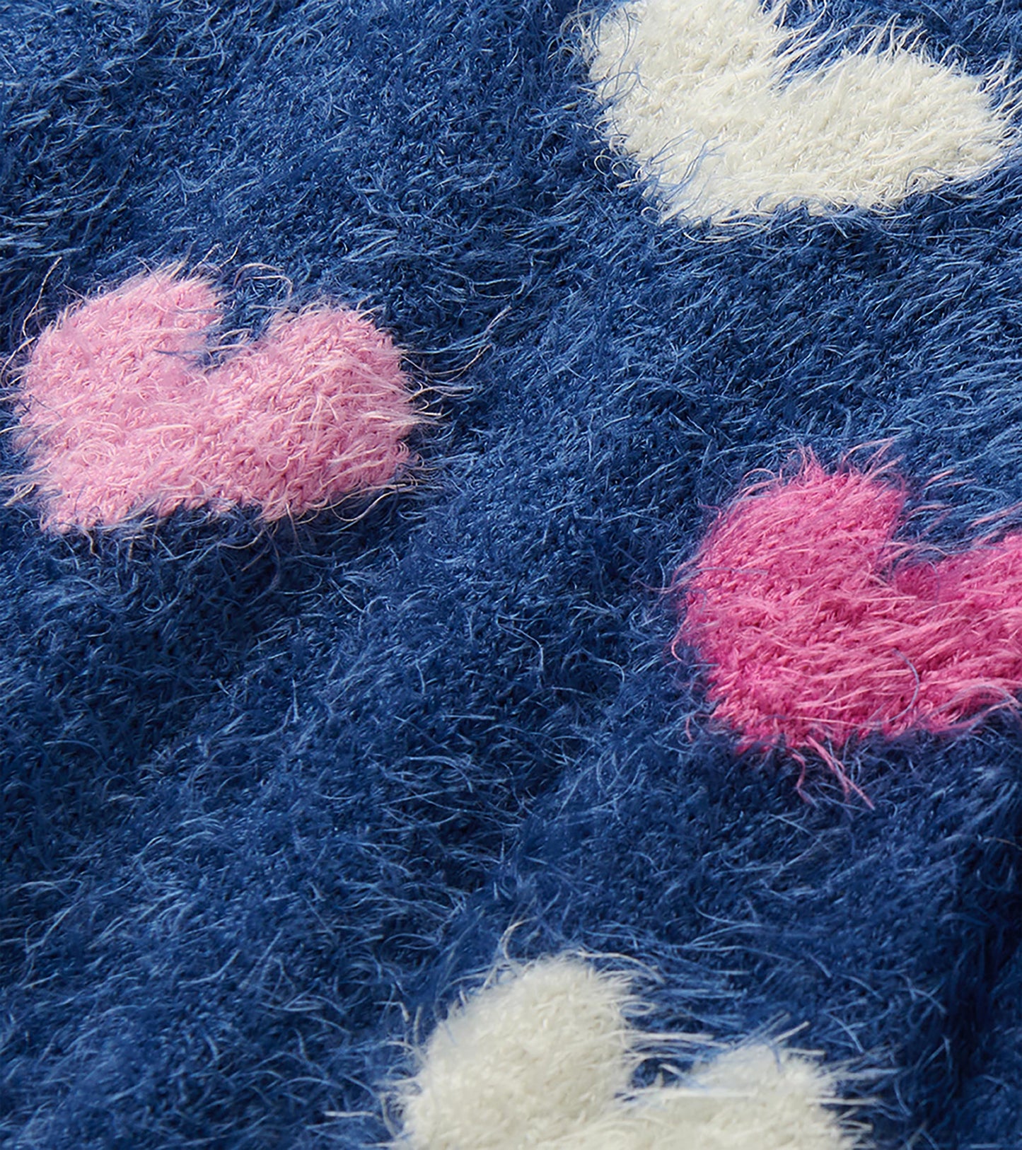 Close-up of fuzzy blue knit with white, light pink, and hot pink heart pattern